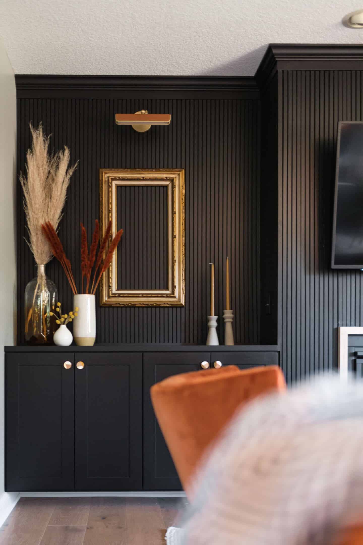 A living room with a black vertical slat wooden panelling wall by Construction2style