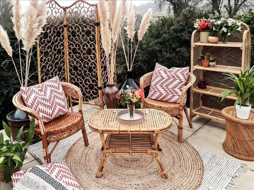 Entertain outdoors by setting up an outdoor living room. Use rattan furniture, rugs, cushions, a coffee table, a shelving unit and a wooden screen.