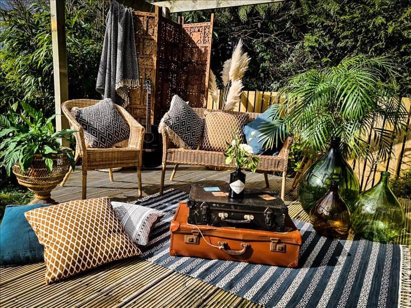 Entertain outdoors by setting up rattan furniture , rugs, cushions, large vases, a wooden screen and vintage suitcases