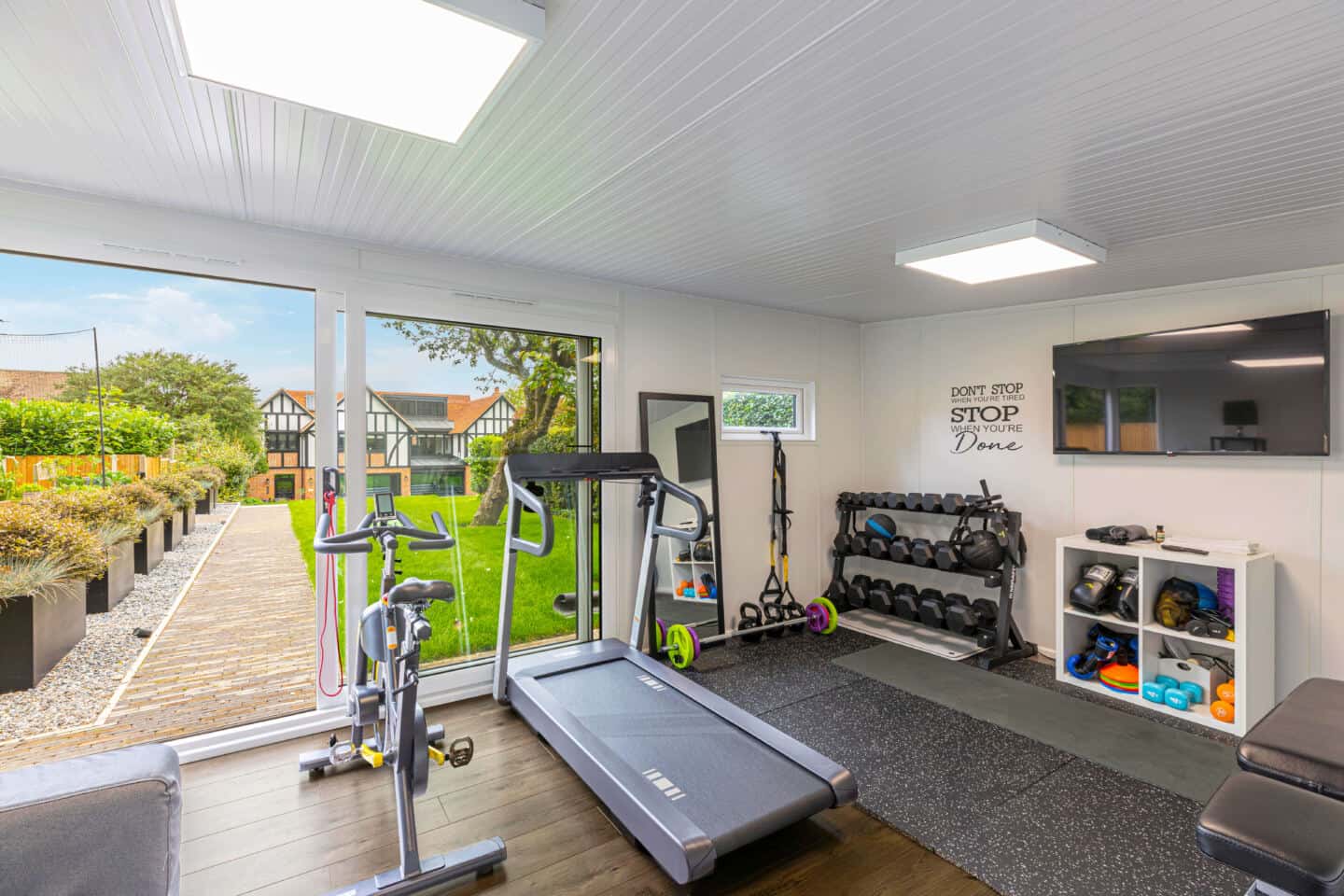 Home gym full of workout equipment and machinery with views out to the garden