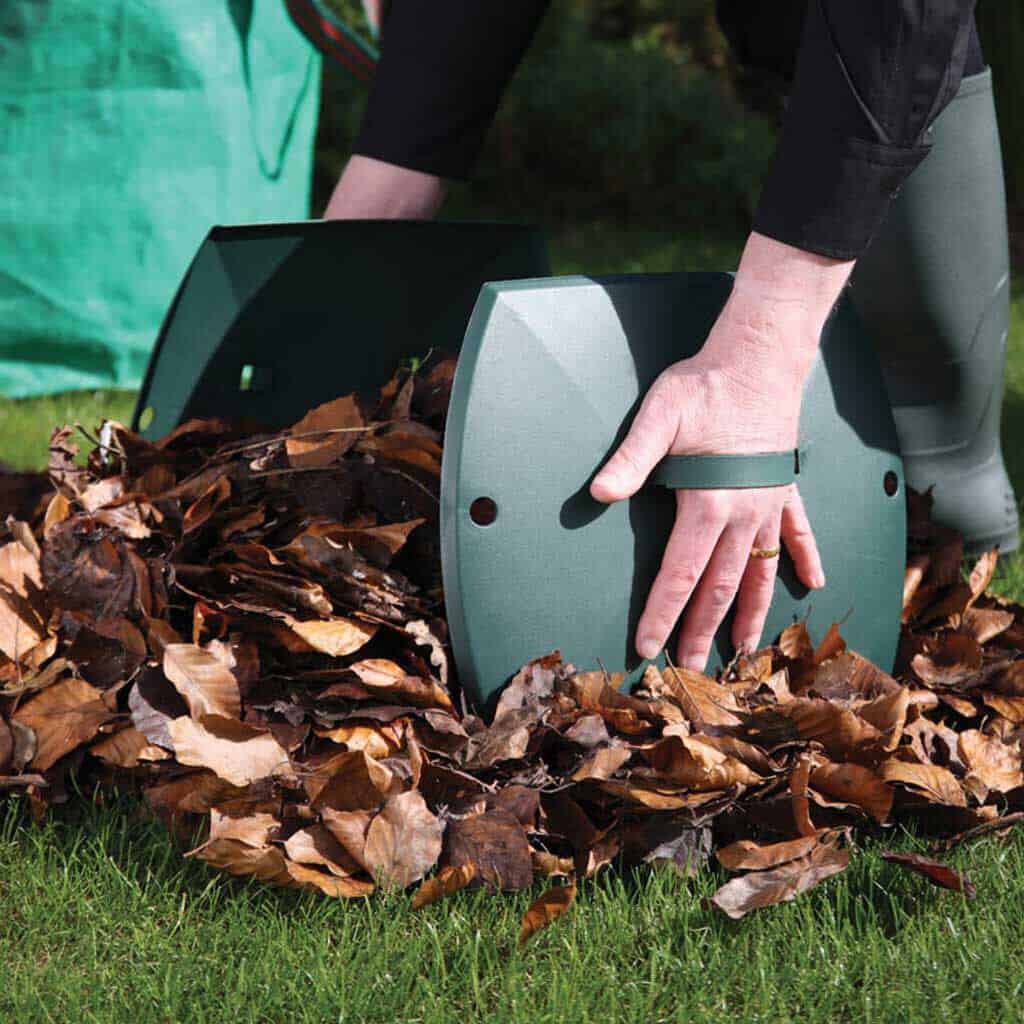 A man bending down to collect leaves with large hand grippers