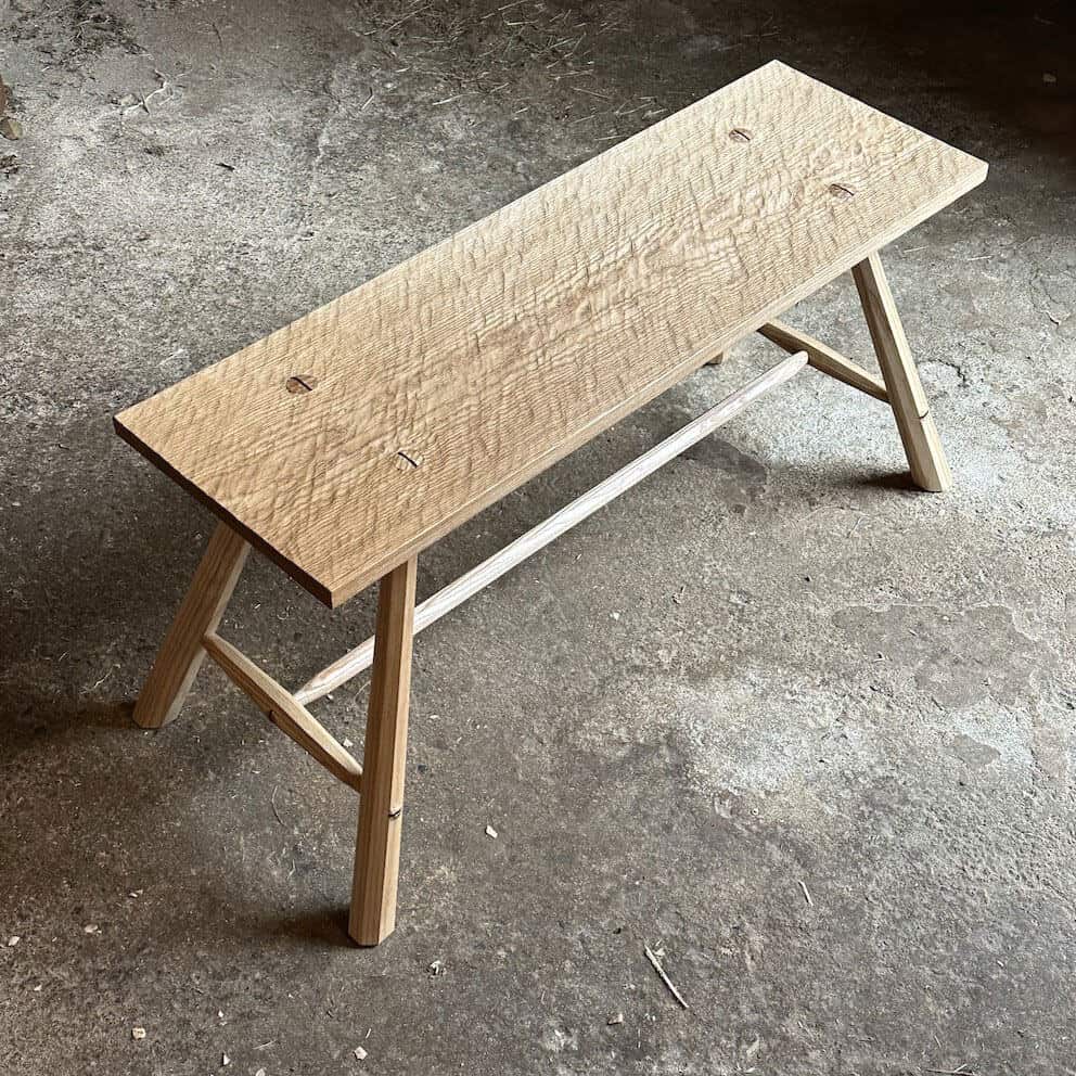 A handmade wooden bench by All in the Making on a concrete floor