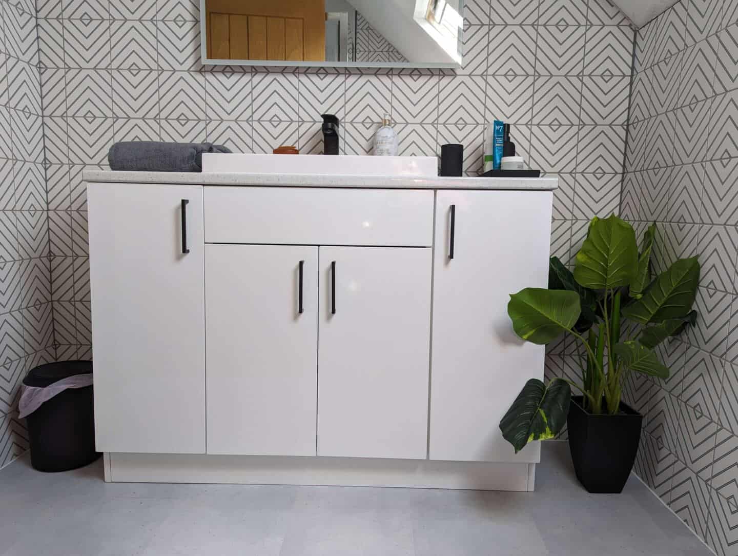 Grey Bath Towel next to a sink on a vanity unit in a bathroom