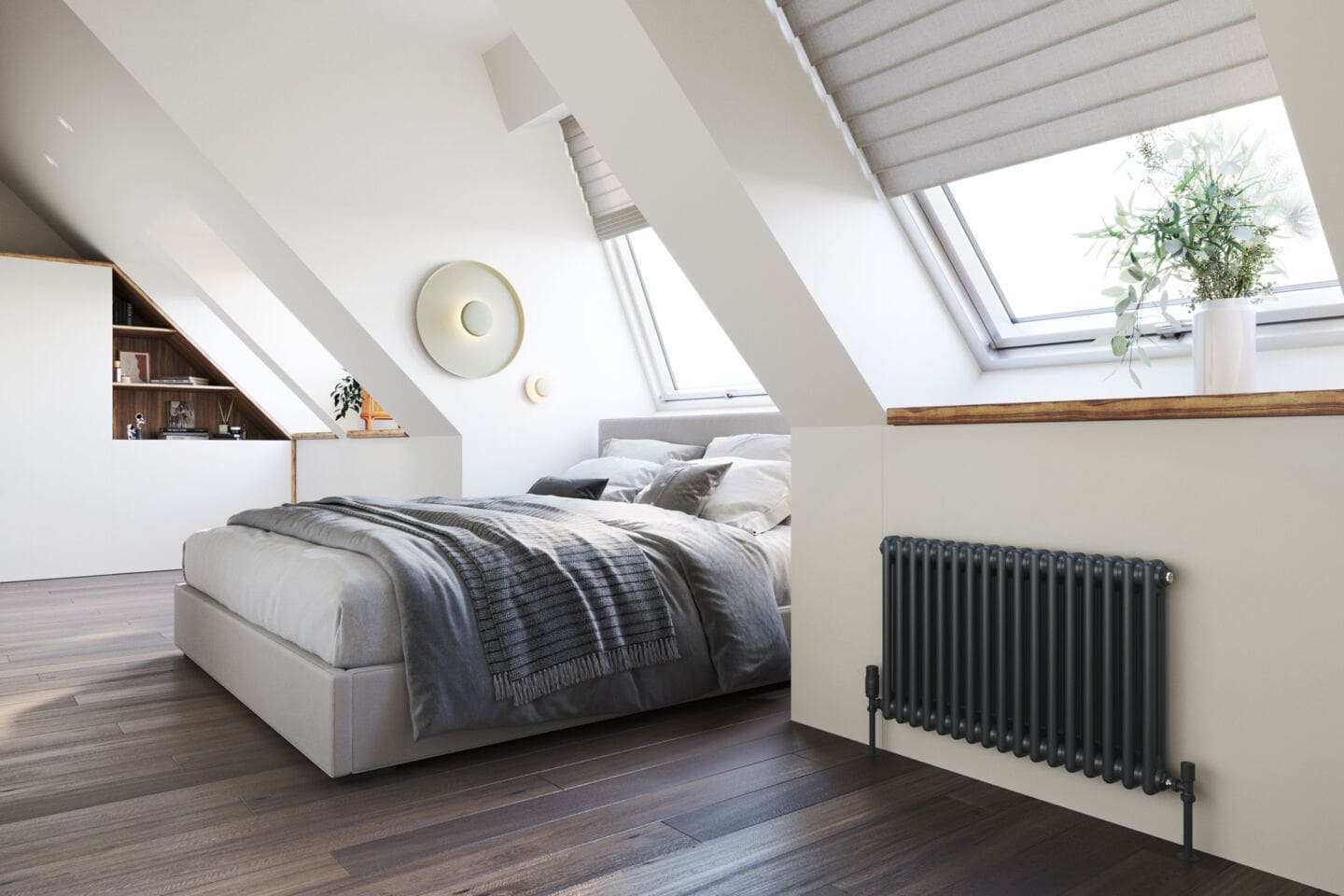 A double bed in a loft bedroom with a grey radiator on the wall beneath the roof windows