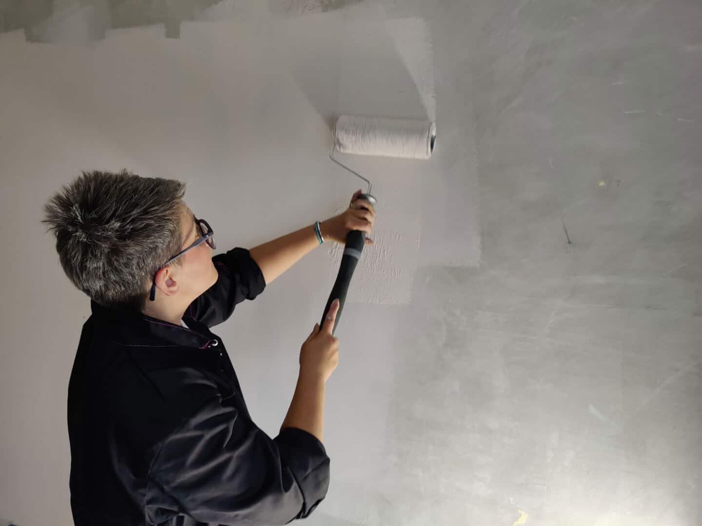 Blogger Stacey Sheppard applying Dulux Simply Refresh Paint to a wall with a roller in preparation for creating a DIY Painted Arch Accent Wall