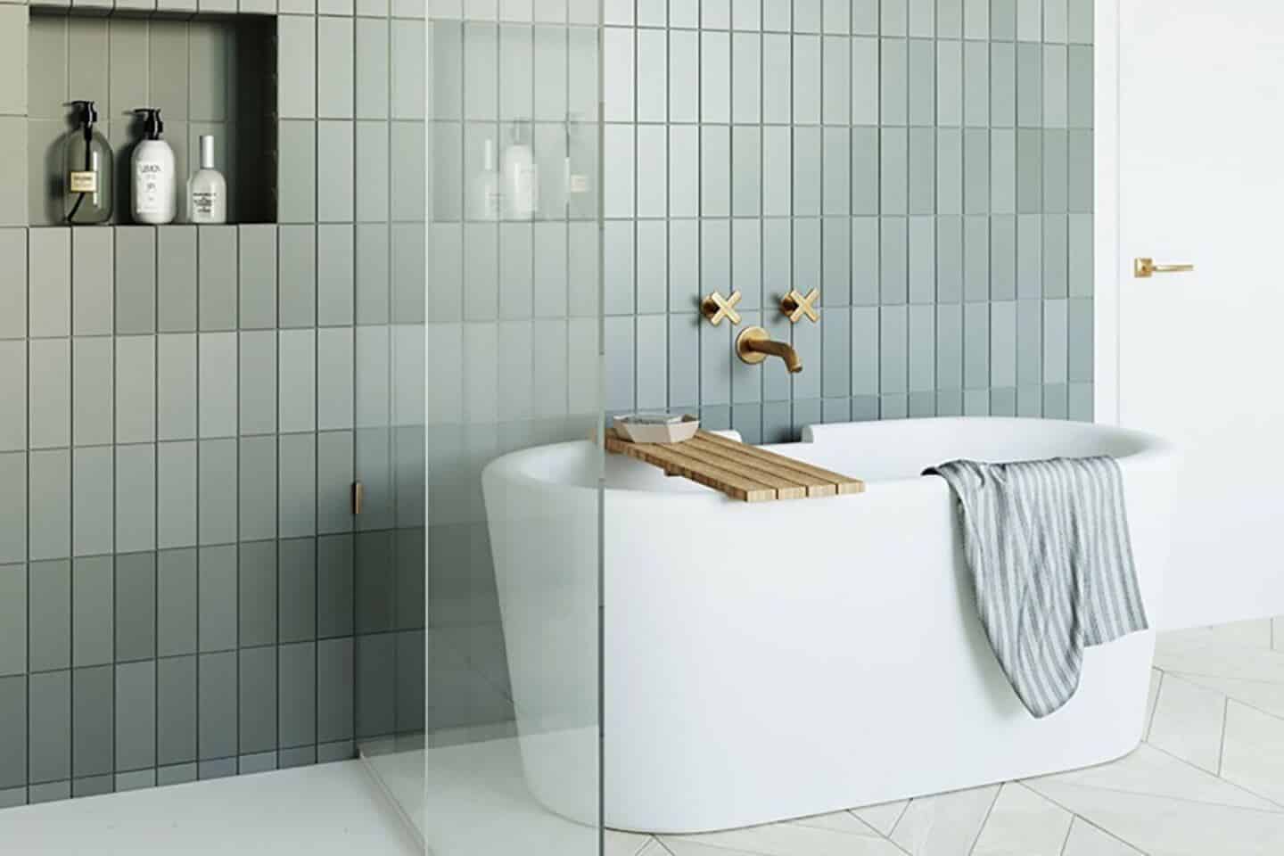 A free-standing bath in a bathroom with tiled green walls