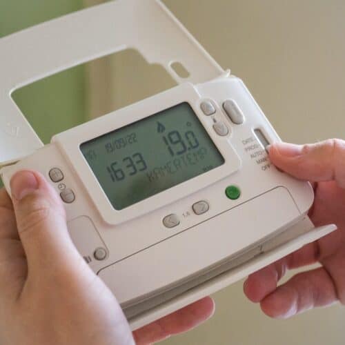 A man holding a heating thermostat