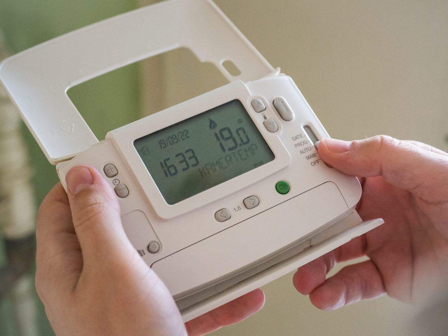 A man holding a heating thermostat