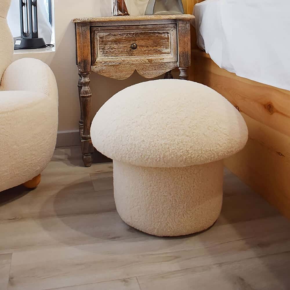 An upholstered mushroom shaped ottoman stool in cream