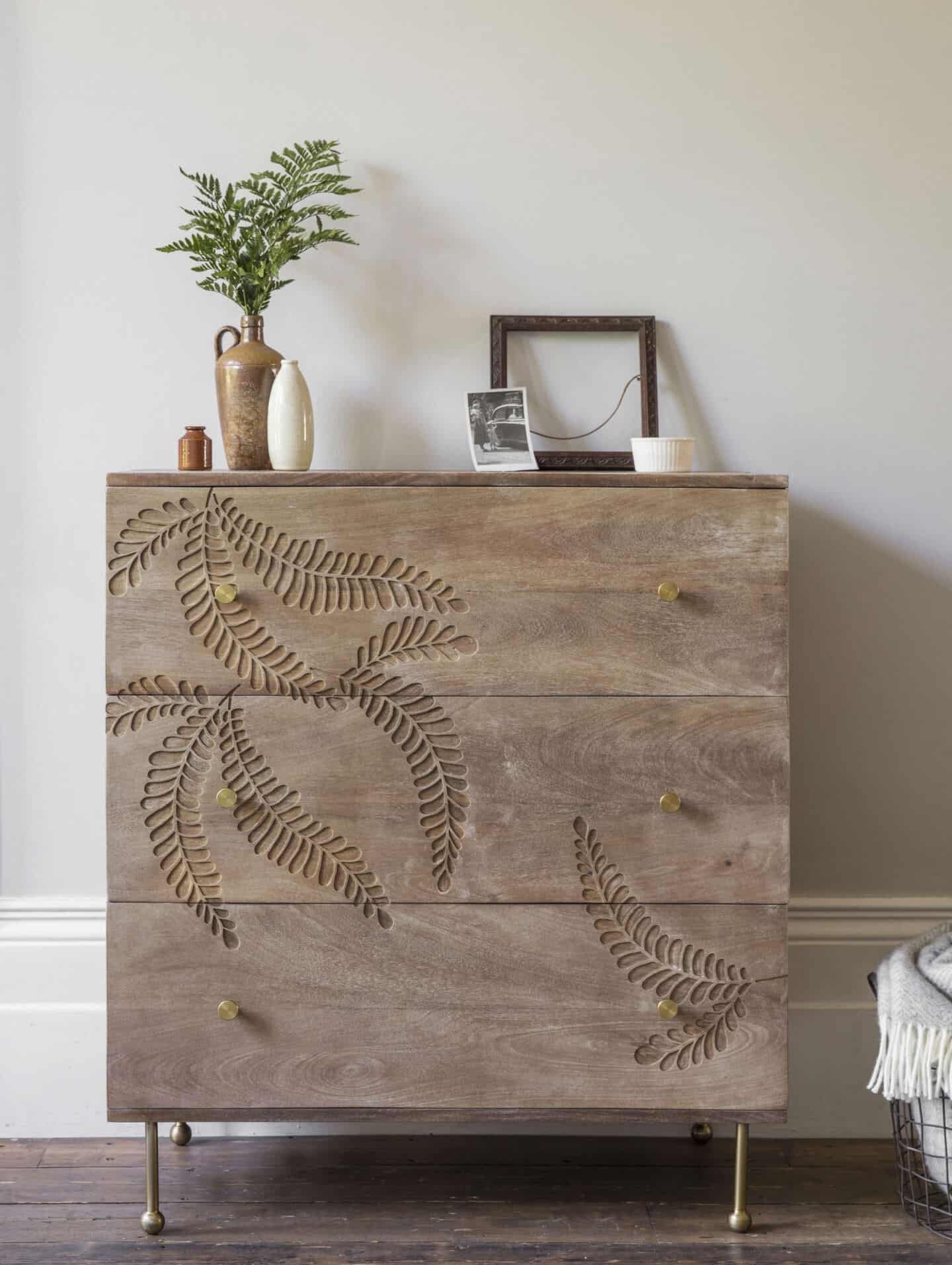 Biophilia in design. A wooden chest of drawers with a large fern leaf etched into the surface