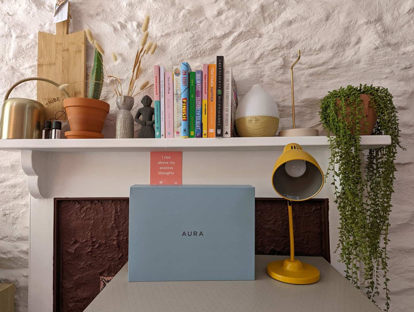 A blue box on a desk next to a yellow lamp. The box contains a digital photo frame