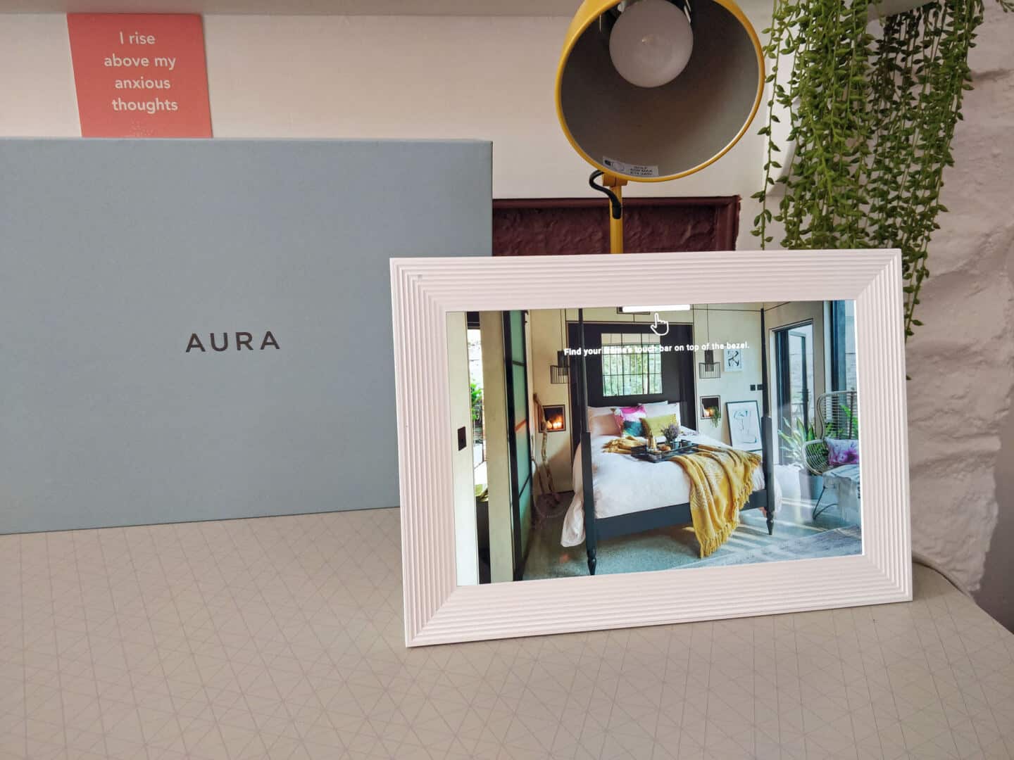 An blue box on a desk next to a yellow lamp. A digital photo frame shows a photo of a bedroom