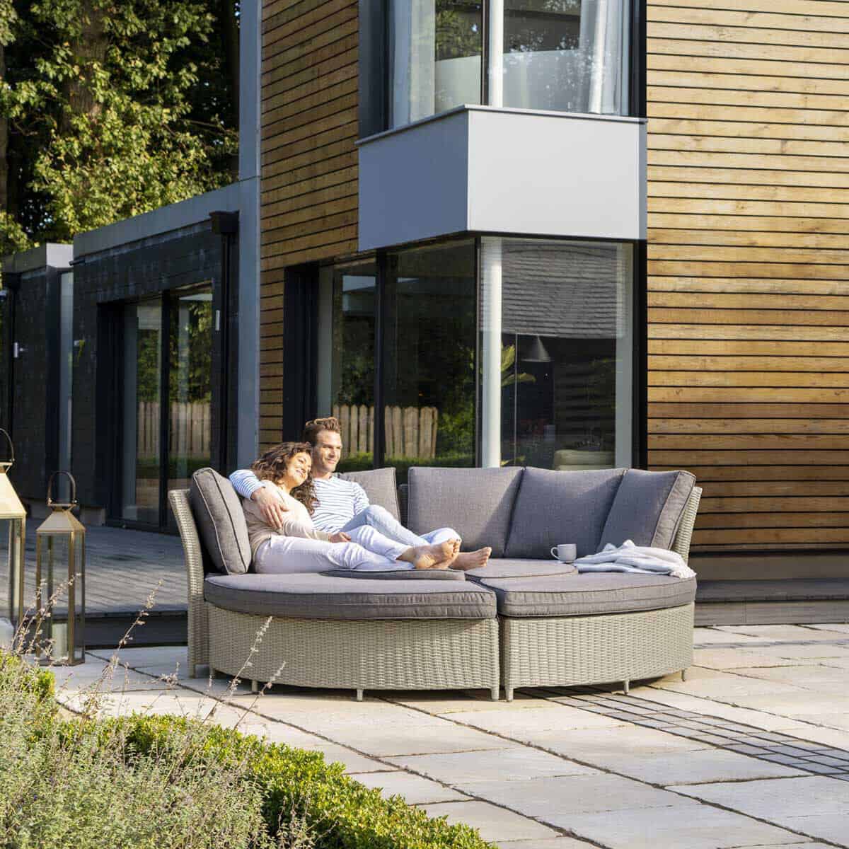 A couple snuggle on a round daybed on a patio