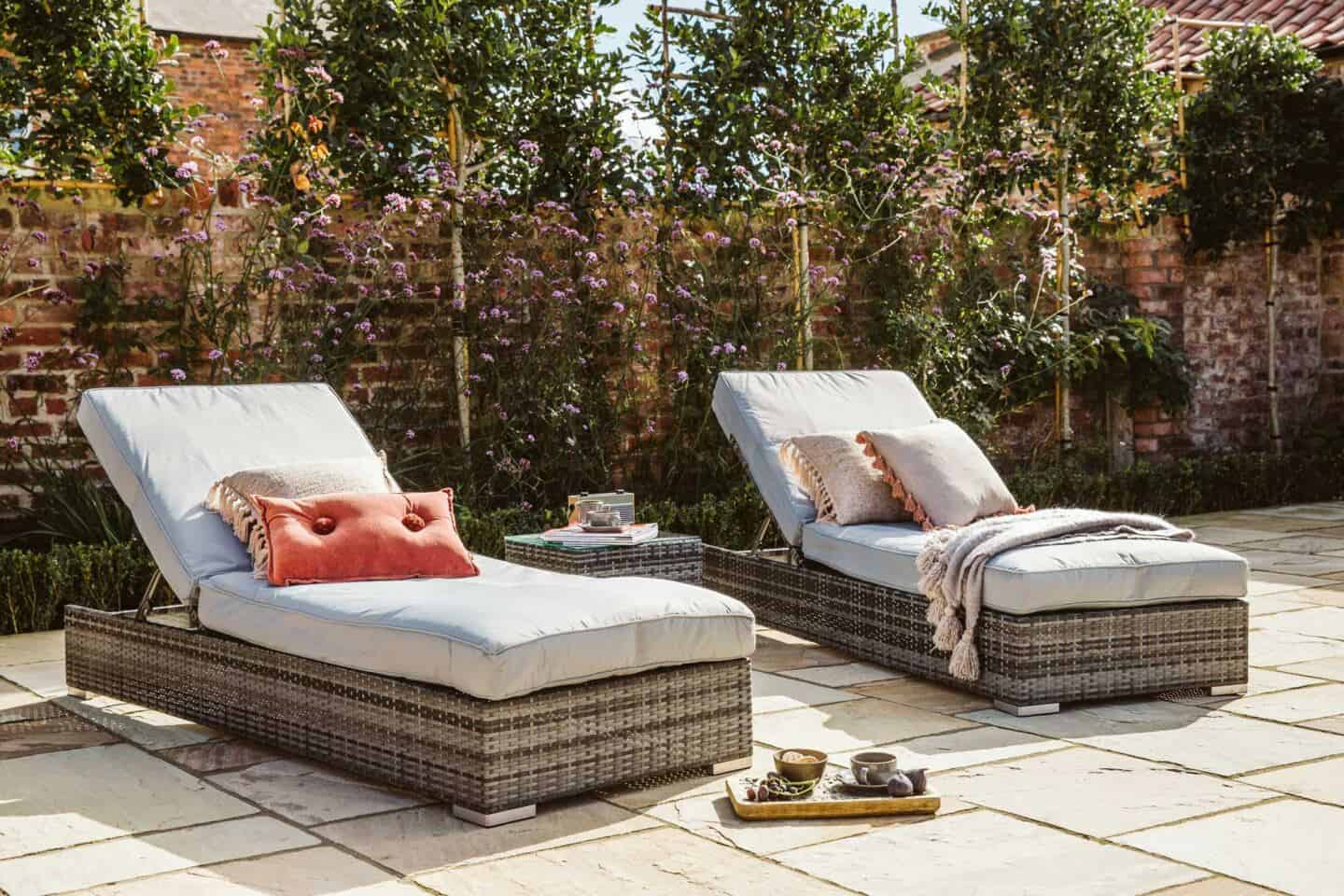 Two padded garden sun loungers from Barker & Stonehouse on a patio with plants behind