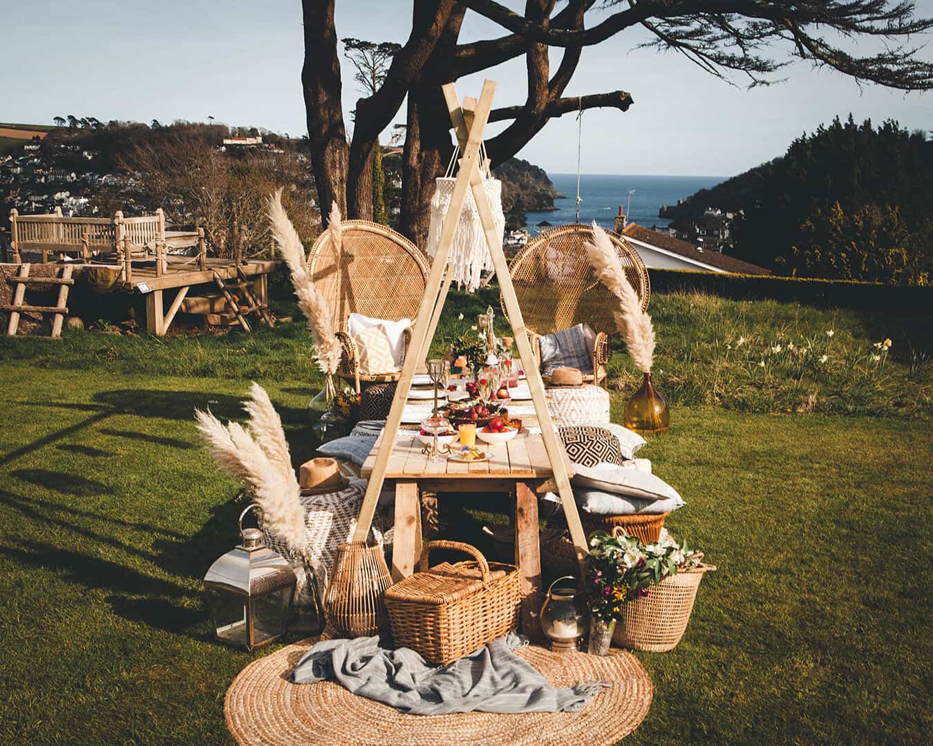 Beautiful boho picnic set up in a garden overlooking the mouth of the river dart