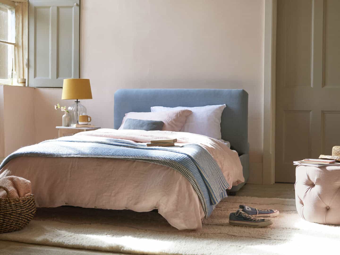 A guest bed made up in a spare room. The bed is covered in linen bedding and linen cushions