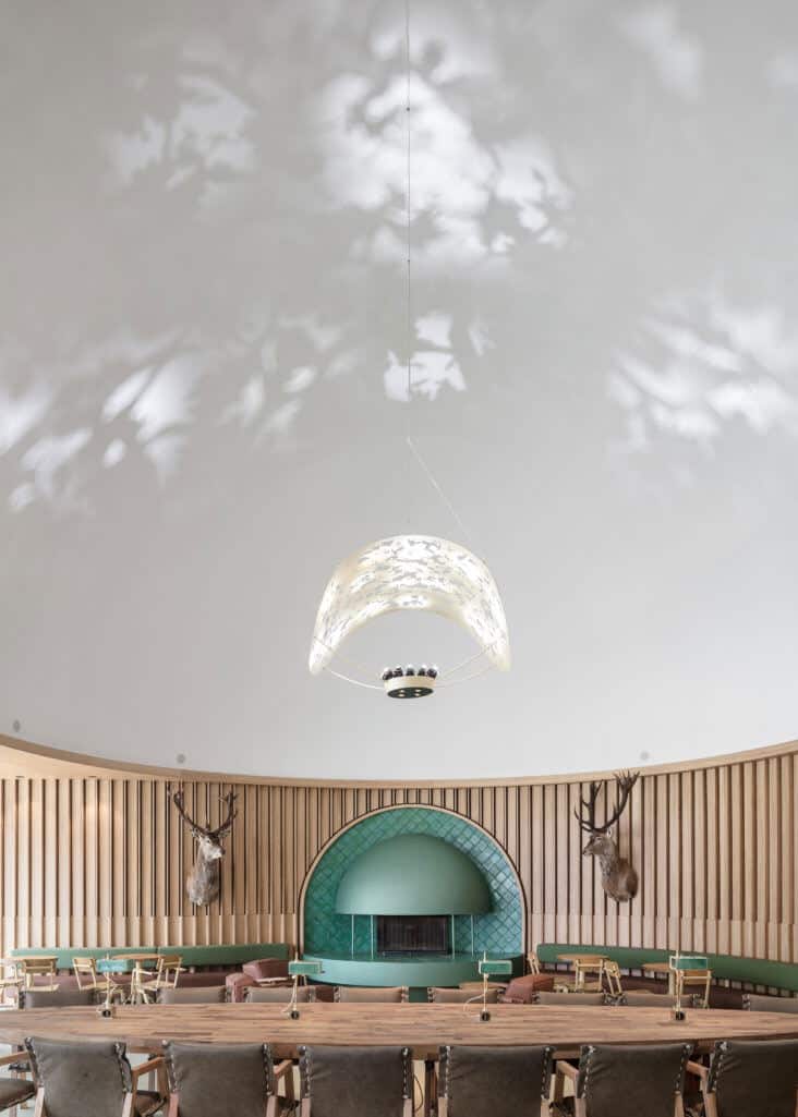 The chandelier in this restaurant casts shadows that resemble light through the tree canopy onto the vaulted ceiling 