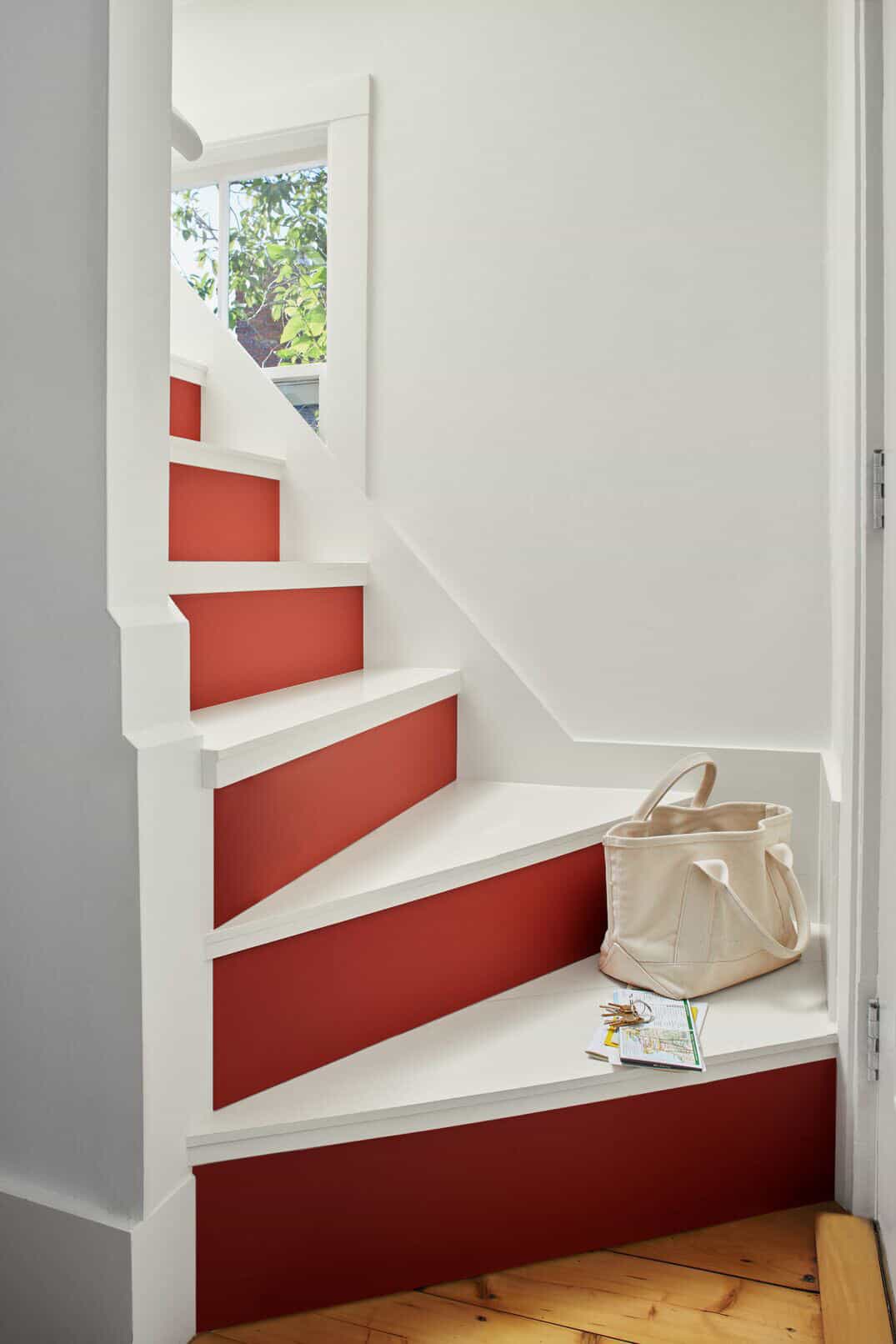 A statement staircase with white treads and red painted risers