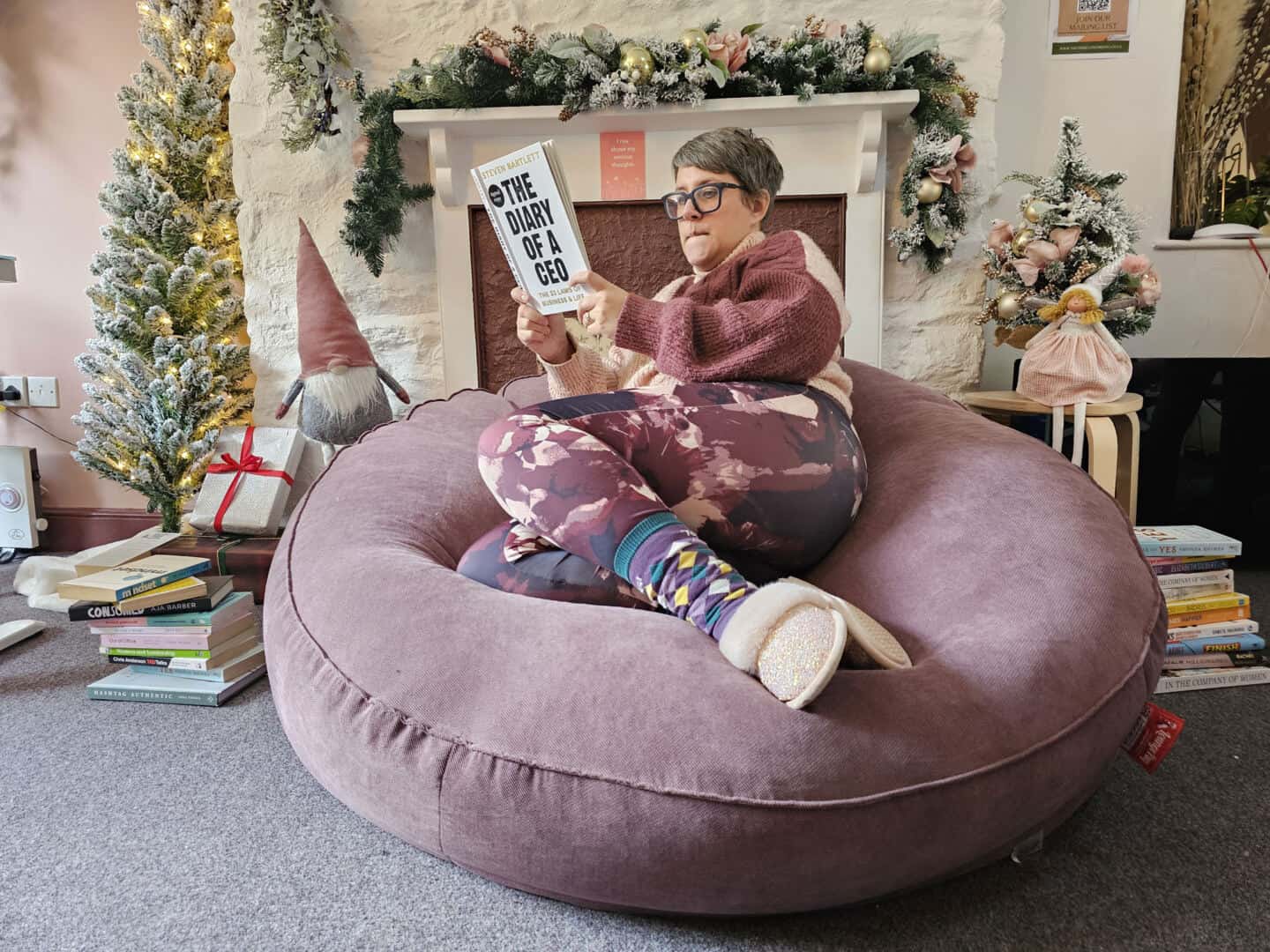 A woman in her forties sat on a huge Big Bertha bean bag reading The Diary of a CEO book