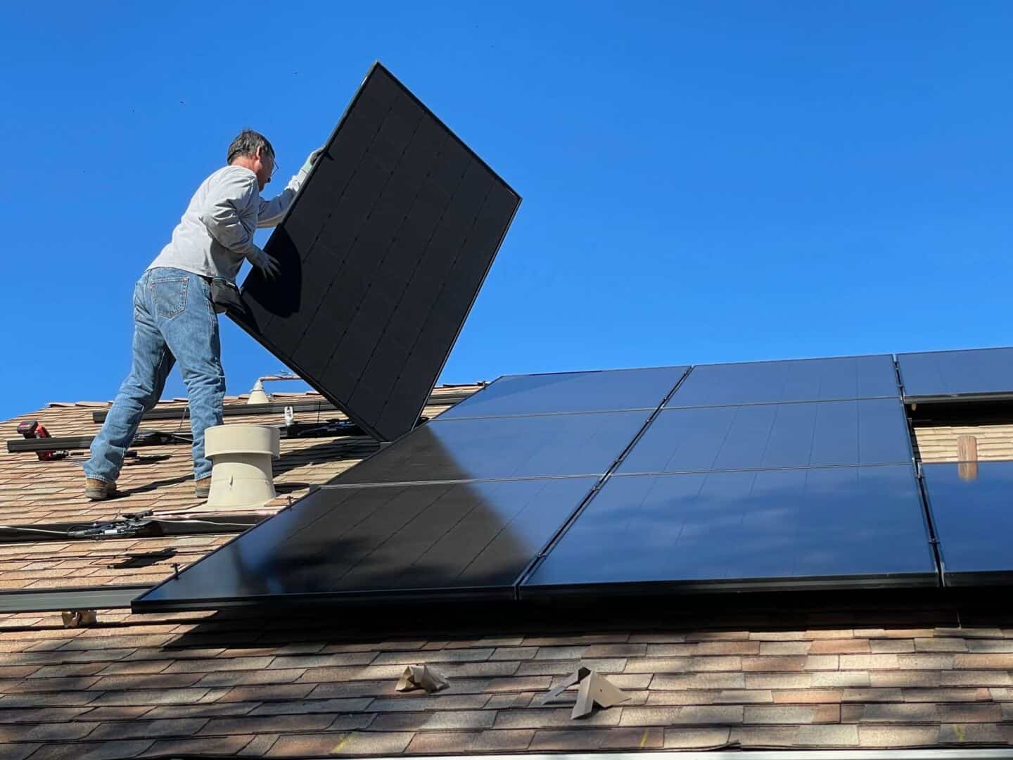 A man installing solar panels on the roof of a house as an eco-friendly home upgrade