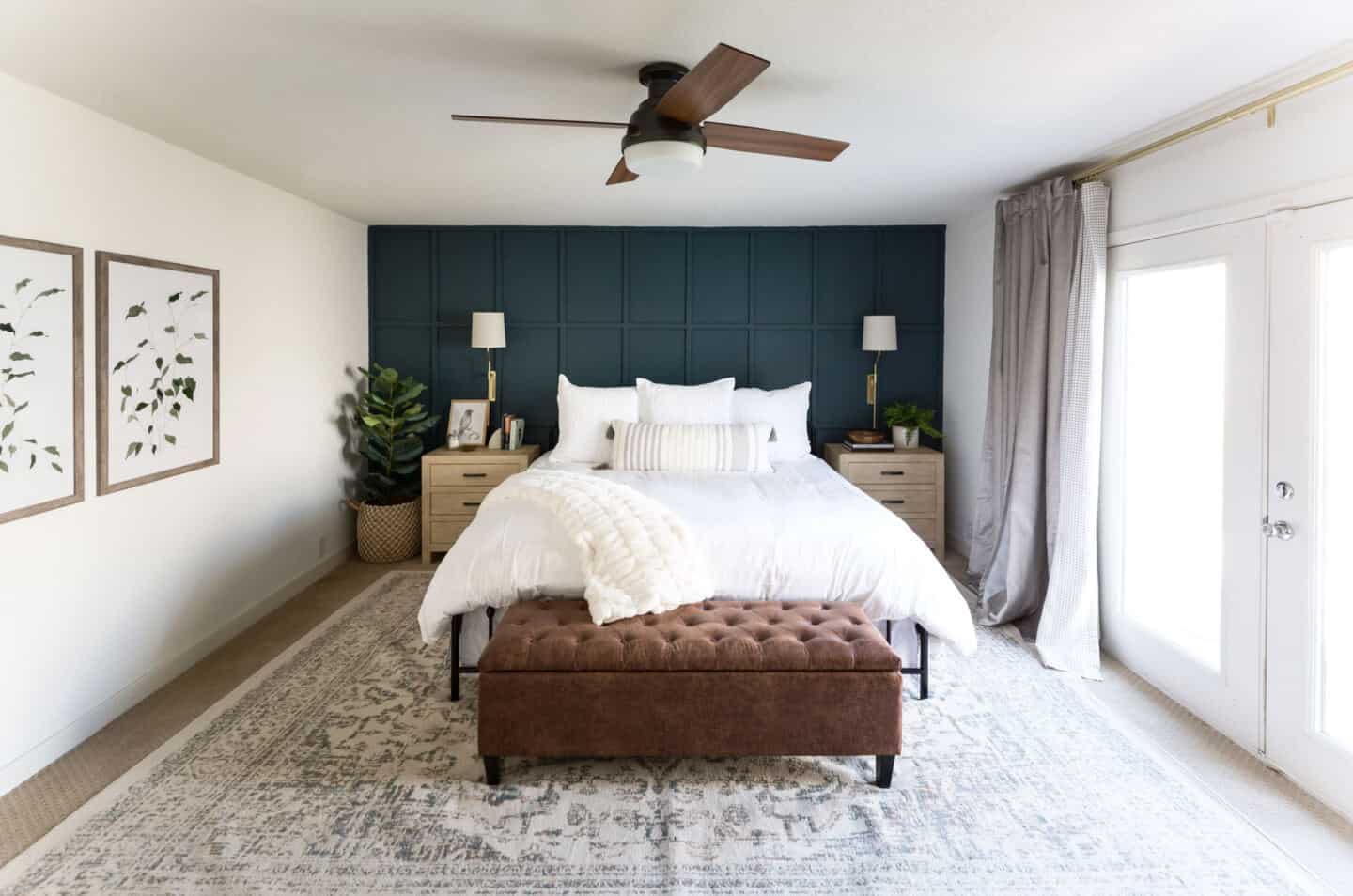 A cosy master bedroom in a farmhouse features wooden panelling in blue on the wall behind the bed