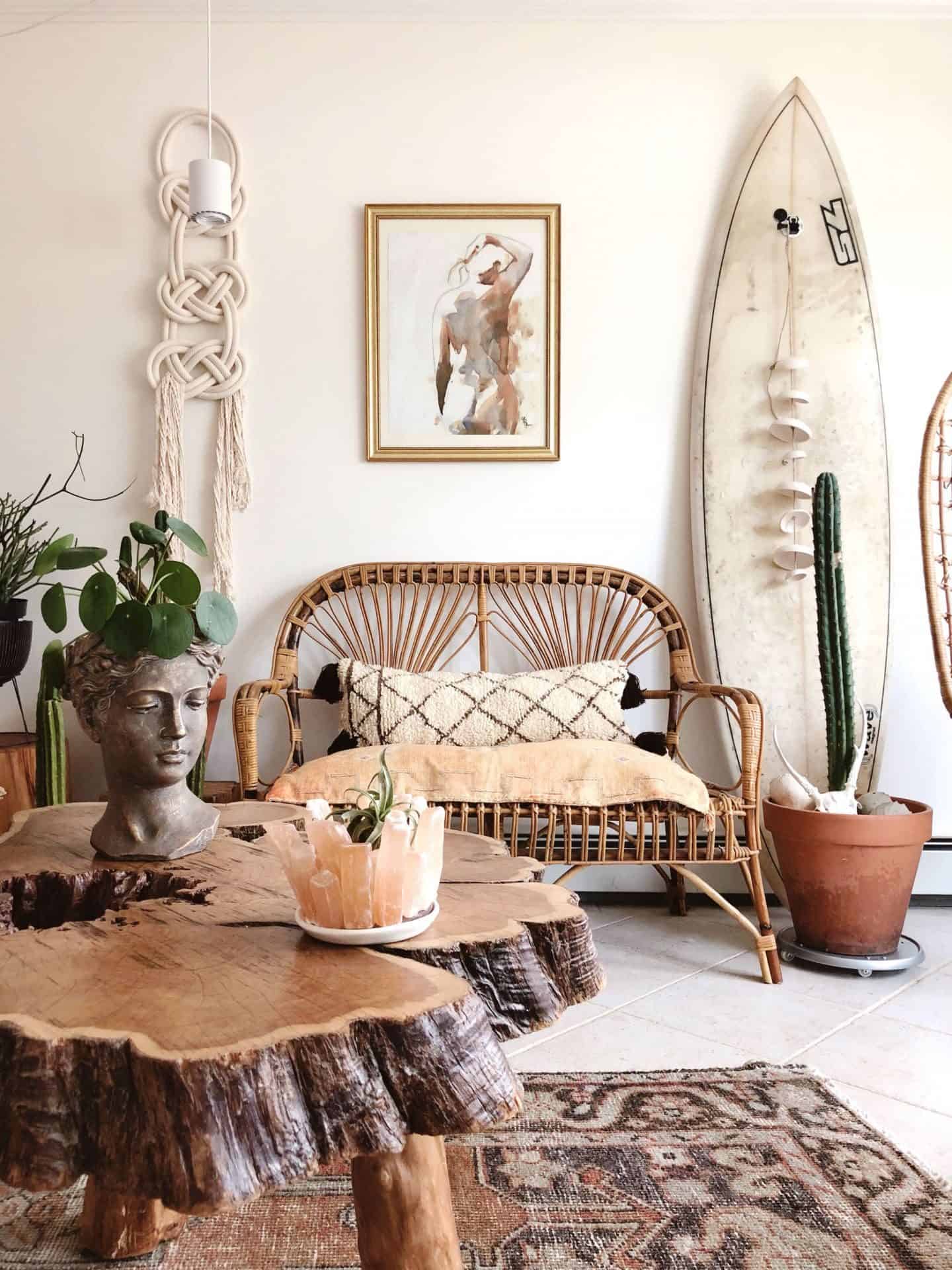 A bohemian style lounge featuring lots of natural materials, macrame wall hanging, terracotta pots and a surf board