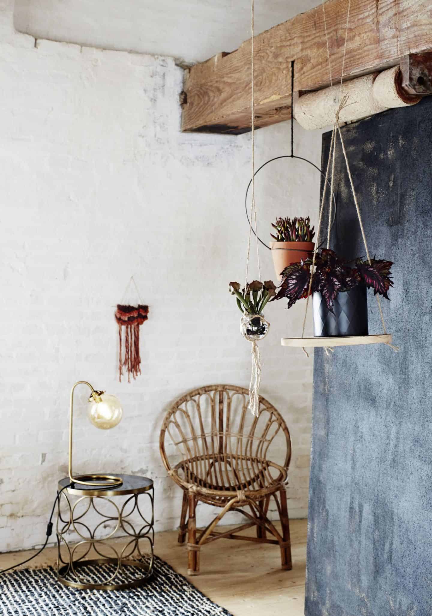 A bohemian style display from Madam Stolz featuring bamboo furniture and plants hanging from the rafters of a rustic style room