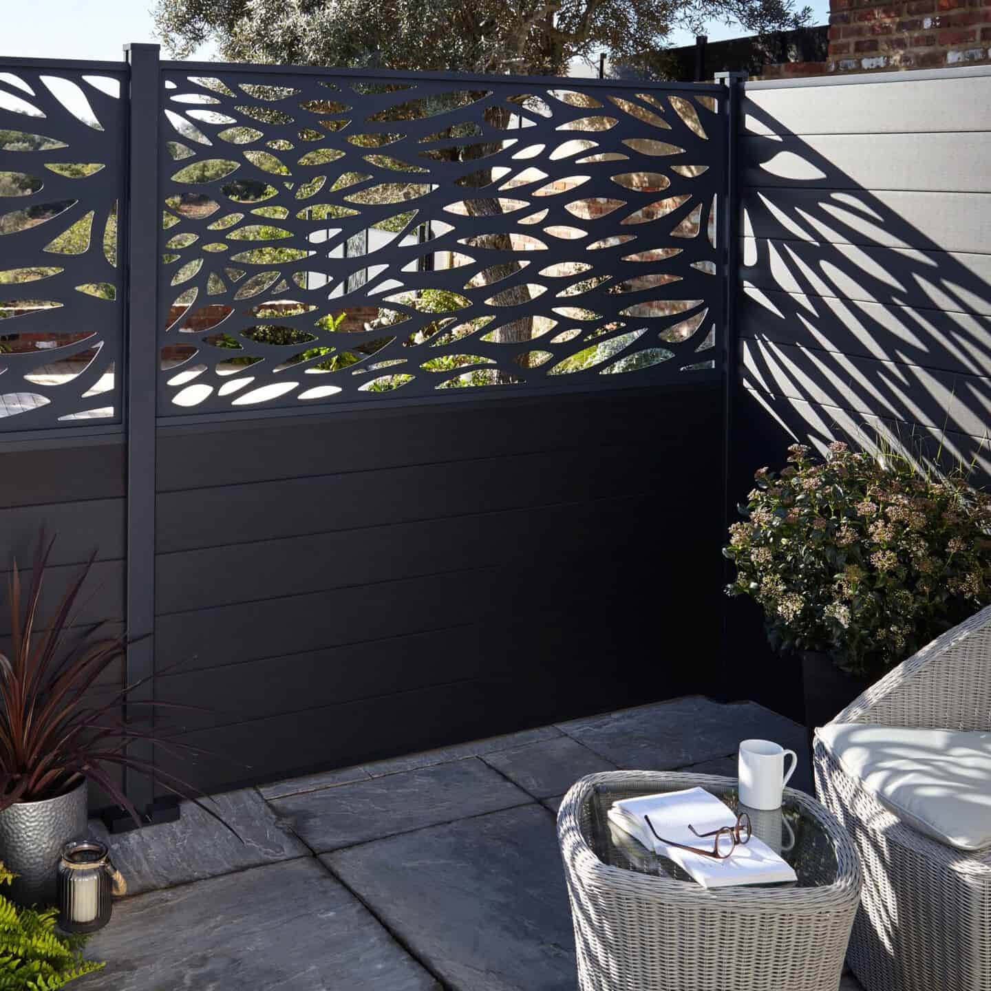 Black composite fencing with decorative top panel with leaf pattern cut out provides privacy in the garden