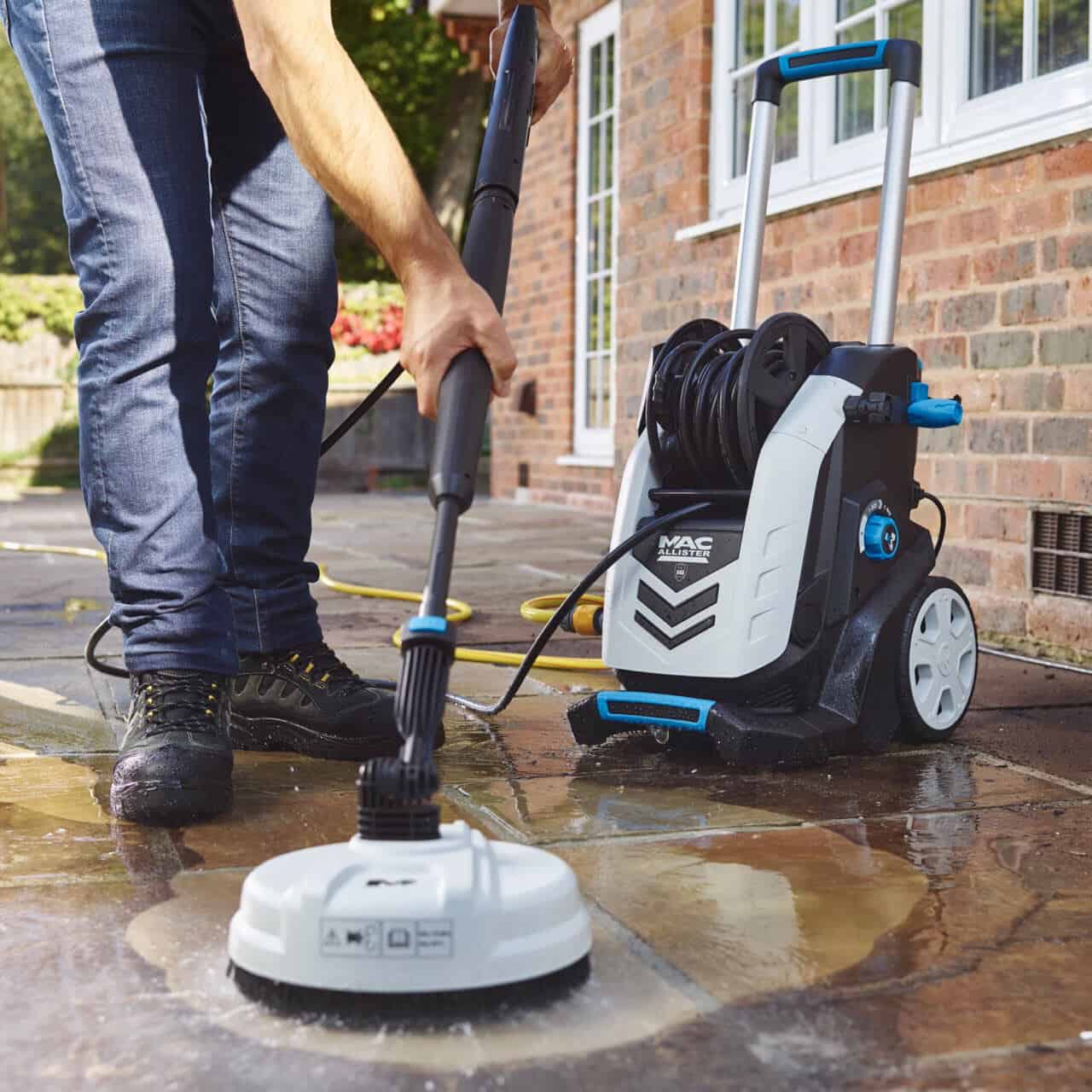 A man using a pressure washer to clean the patio in his low-maintenance garden