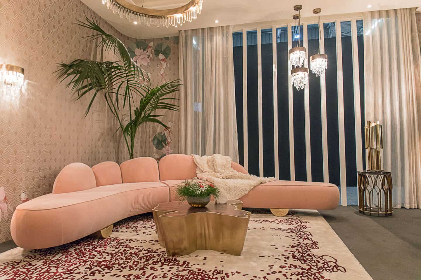 A pink curved sofa with a large window behind and an organic coffee table in front