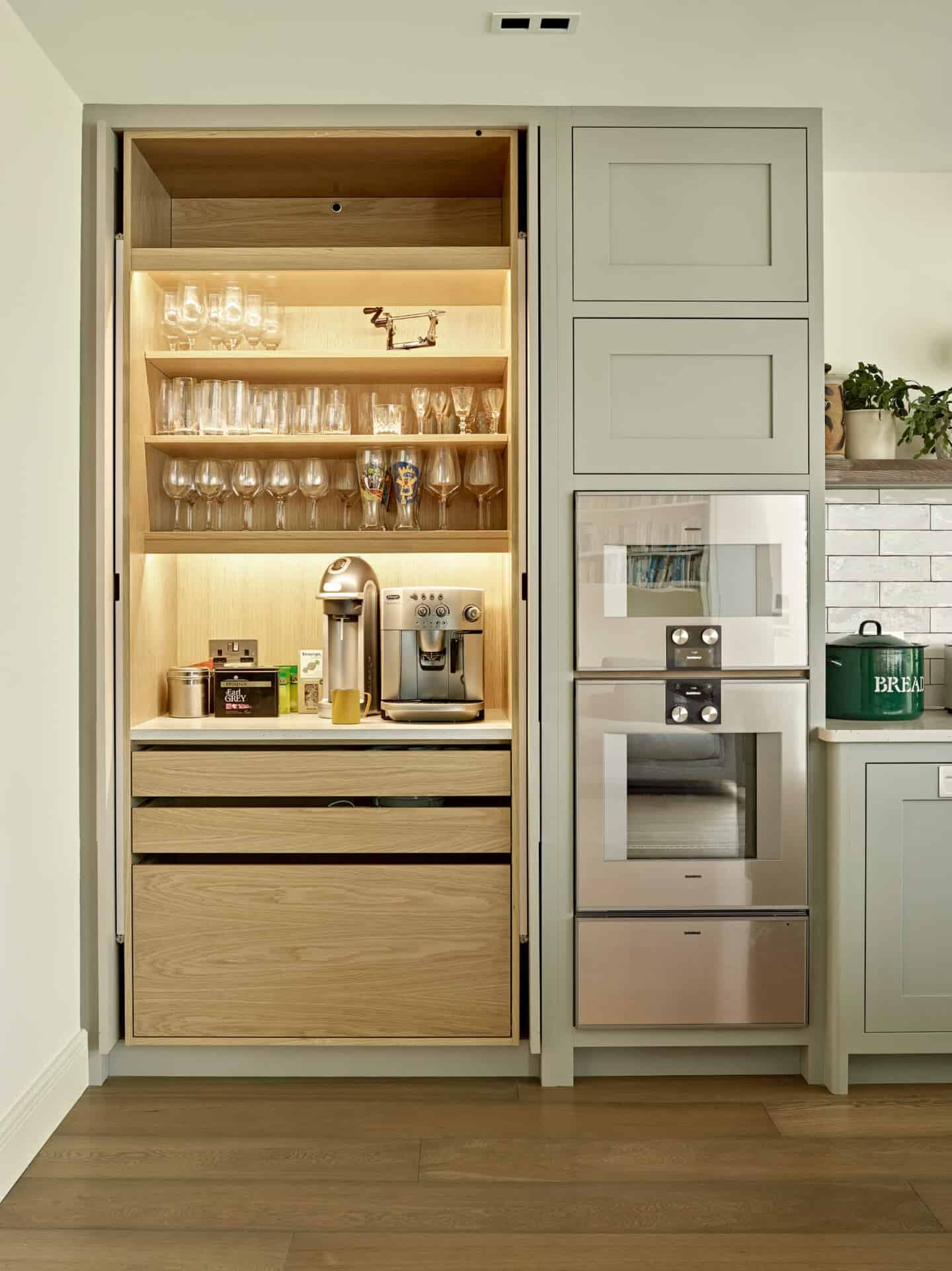 A sage green kitchen featuring a pocket door pantry cupboard to conceal small appliances