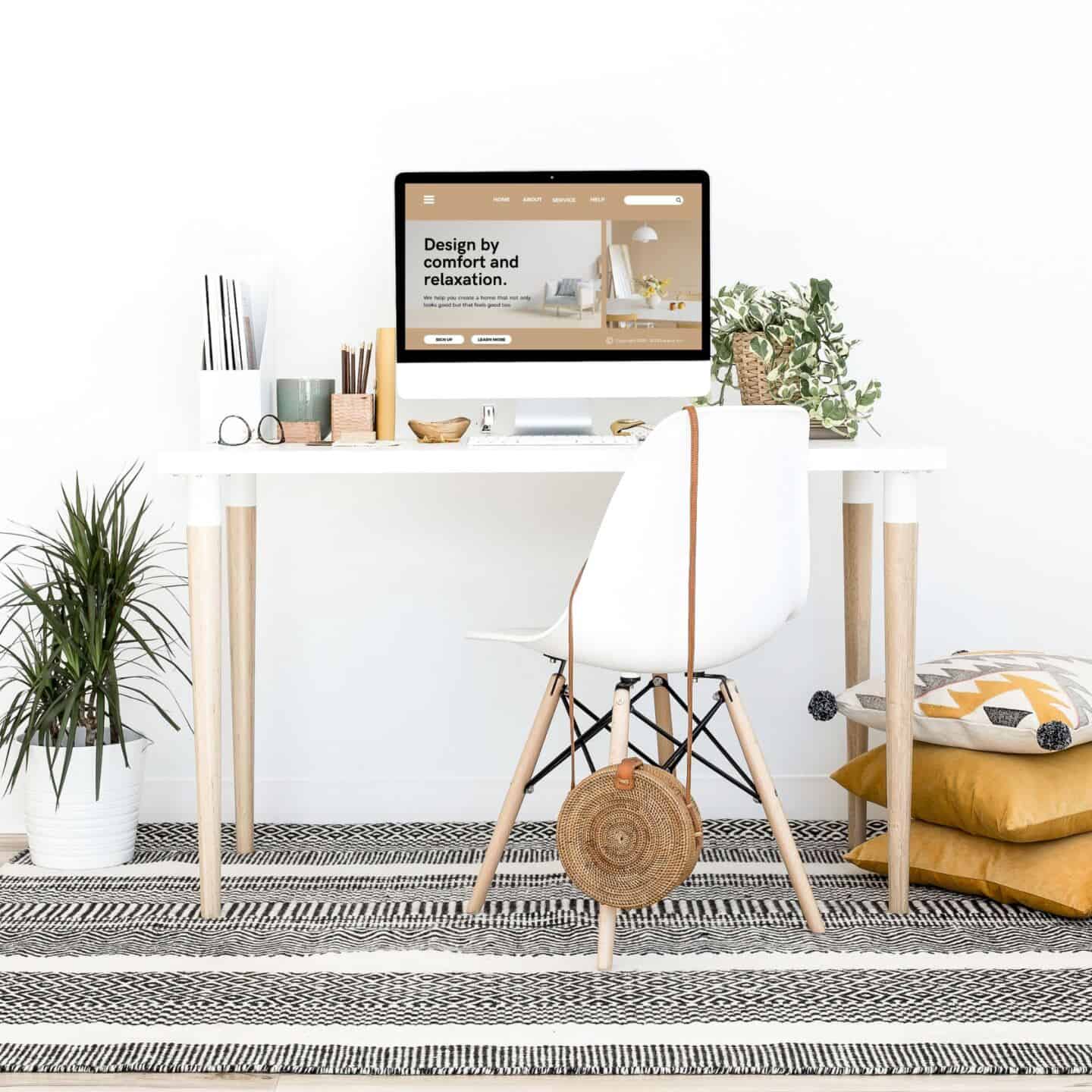 A desk on a monochrome tribe with a tribal pattern. On the computer screen is an interior design website