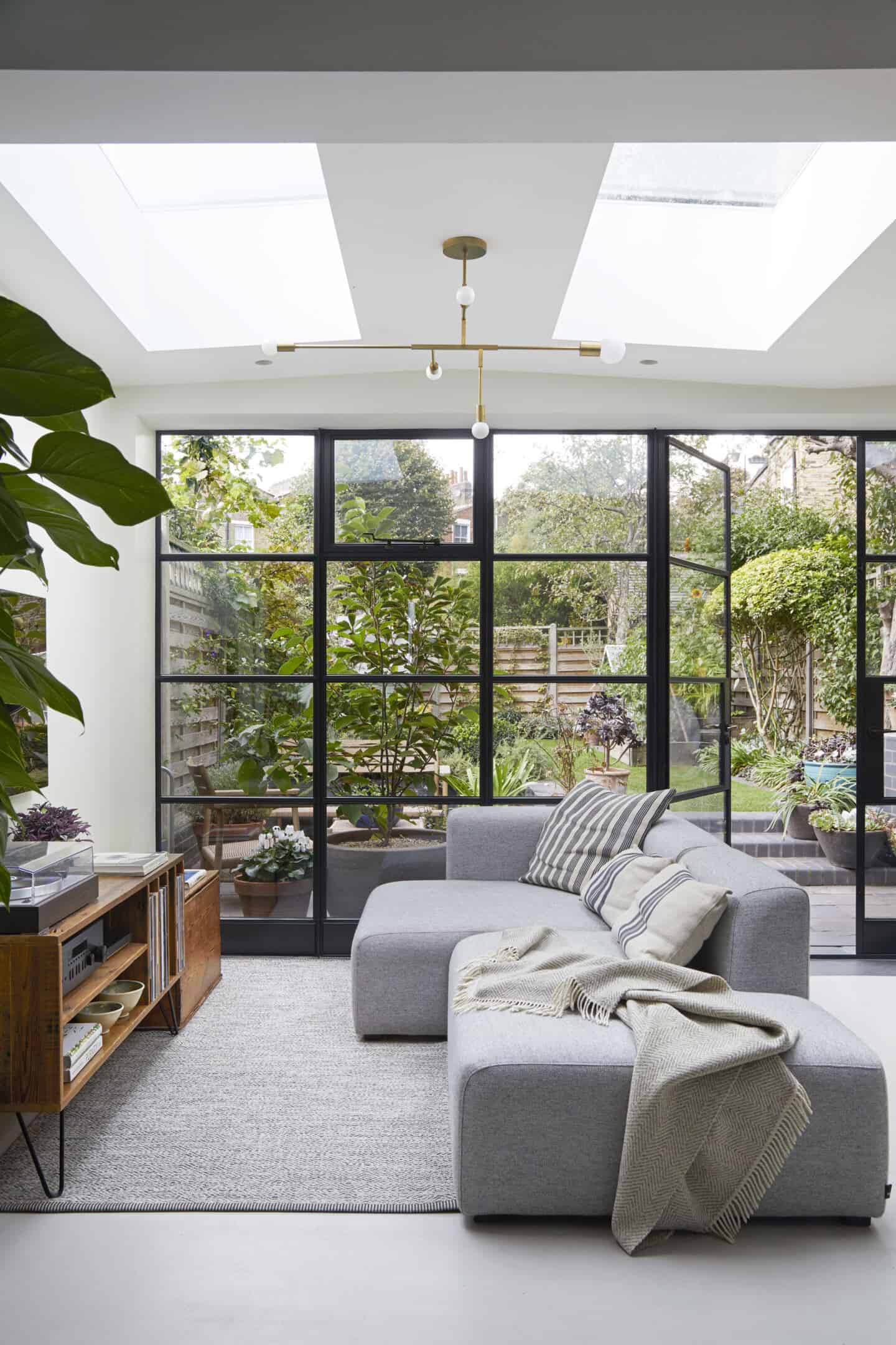 A light filled living room with a glazed wall separating it from the garden