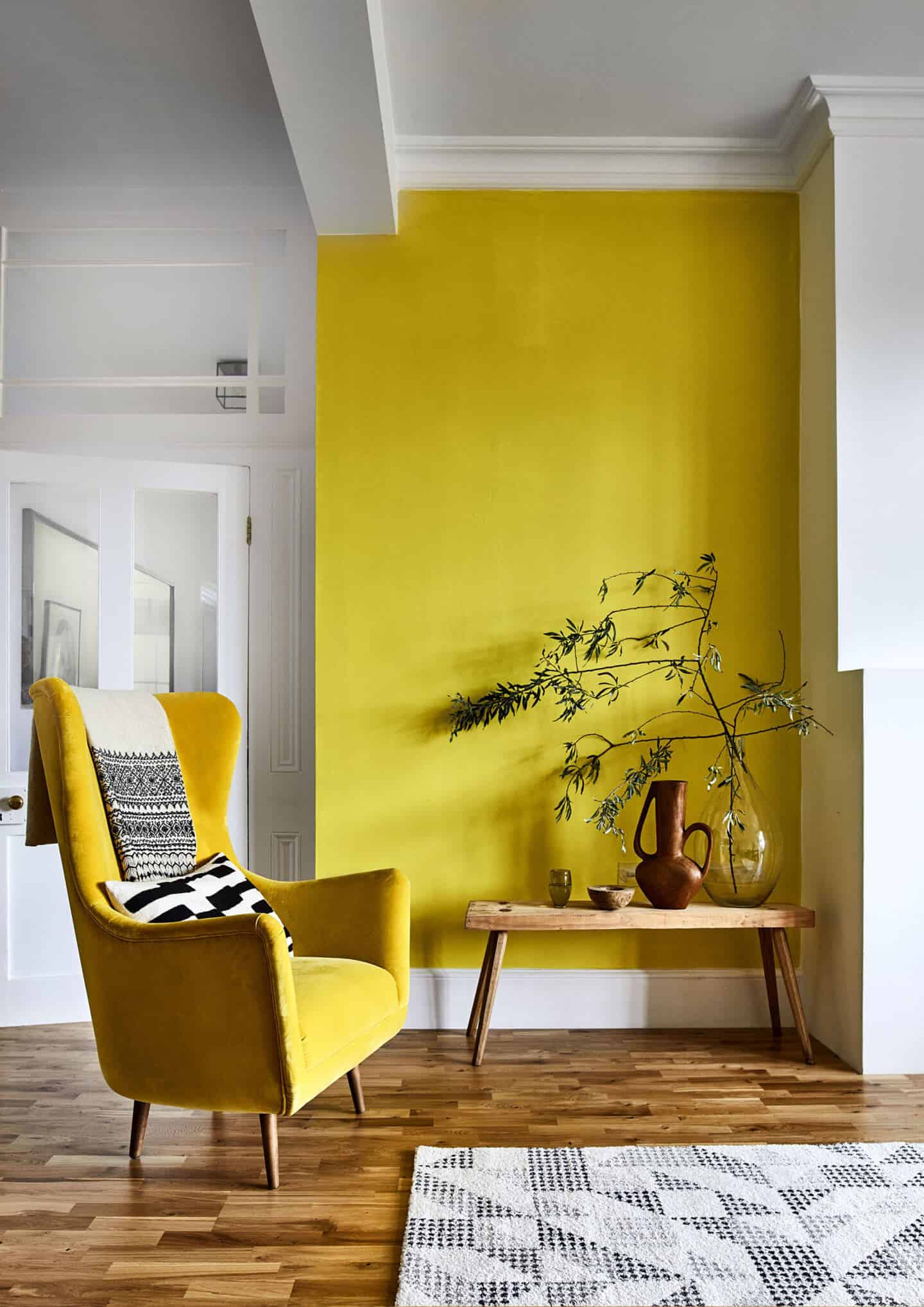 Pantone Colour of the Year 2021 - Illuminating. The colour psychology behind using yellow in interiors. A yellow arm chair against a yellow wall. Wood flooring from Carpetright.