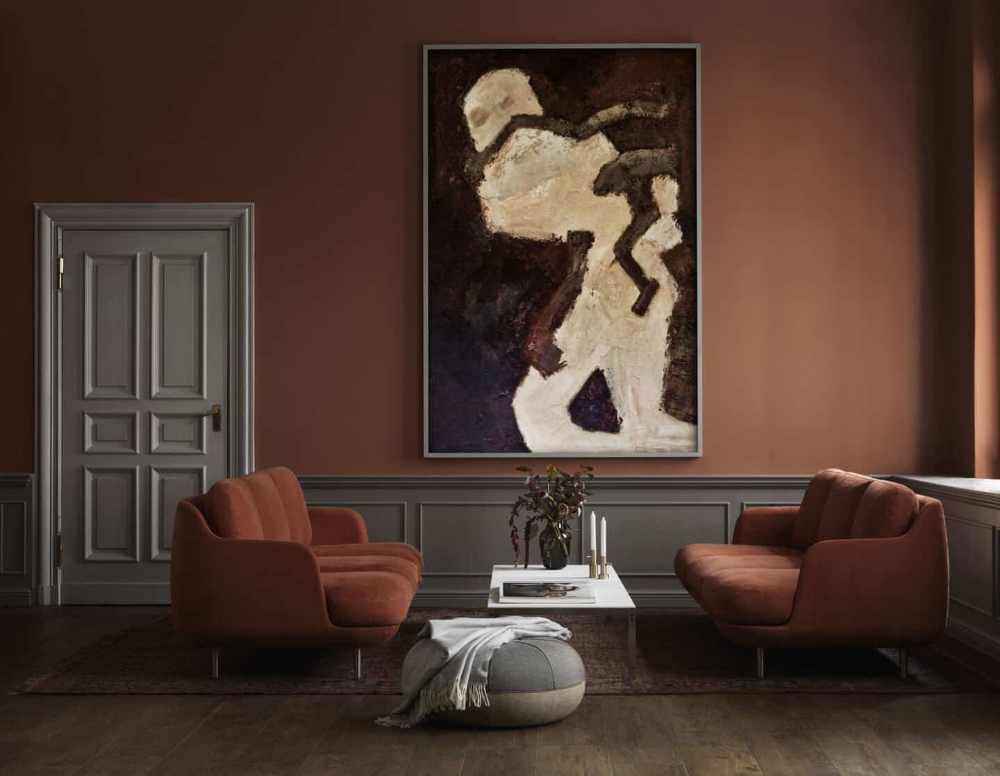 Autumnal Hues in interiors - A living room set up featuring two sofas facing one another either side of a coffe table, with a large piece of abstract artwork hung on the wall behind.