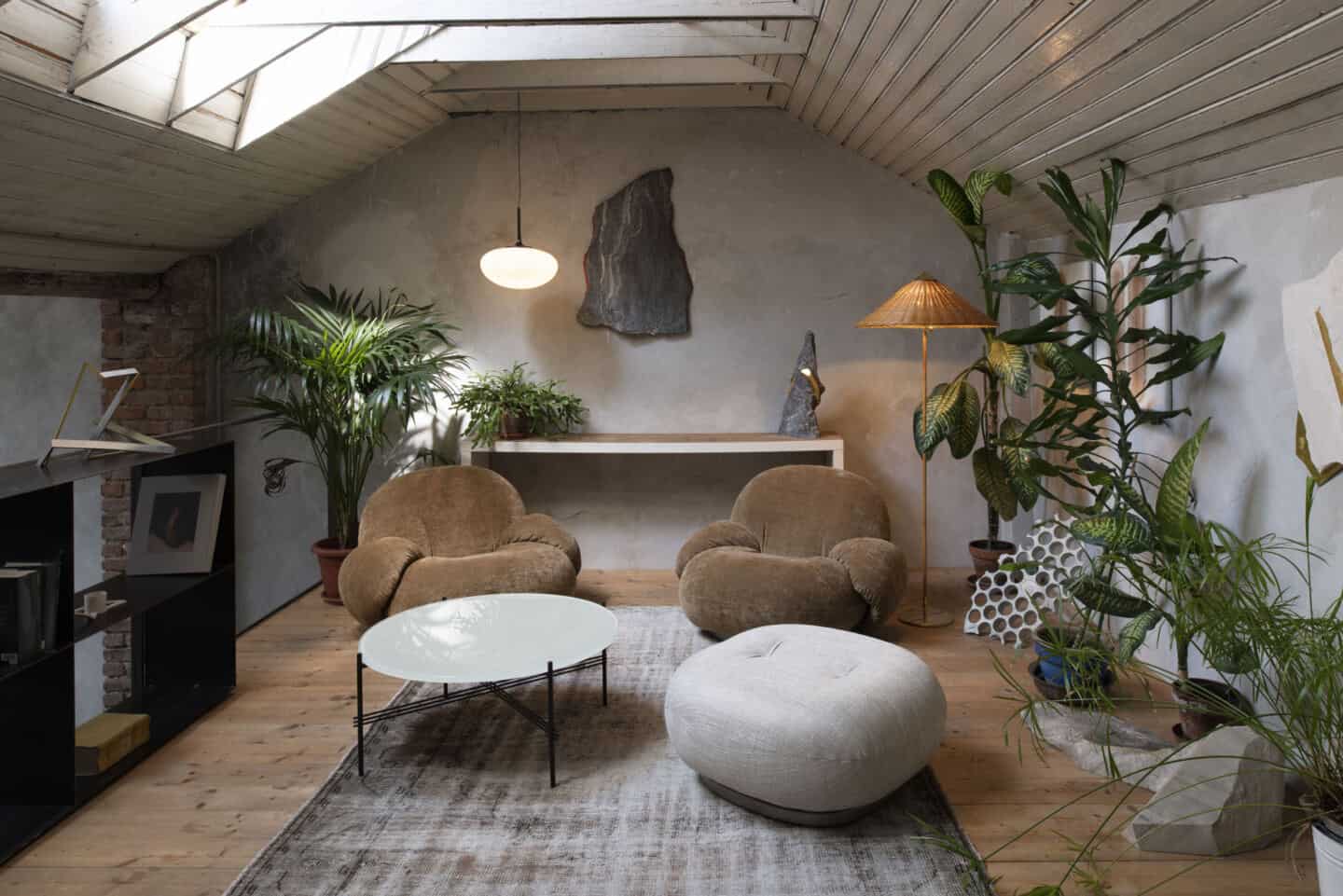 A couple of Pacha lounge chairs by Gubi sit in a loft room full of plants and natural textures. A perfect example of how to use organic shapes in interiors