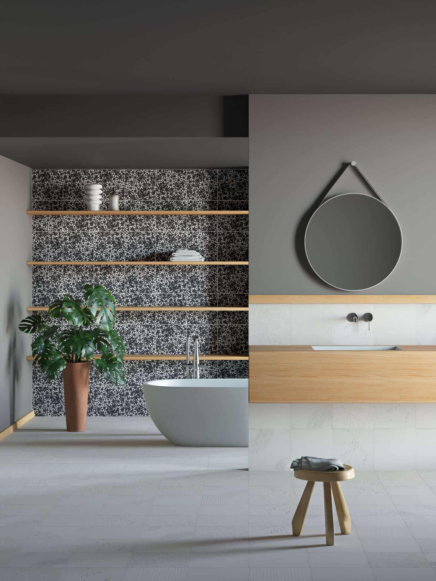 A large bright and airy bathroom with monochrome small flower print tiles on the wall, a freestanding white bathtub and a large Monstera plant in the corner. 