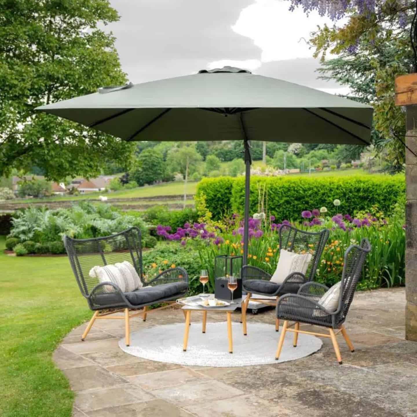 a garden sofa and chair set under a large parasol on a patio