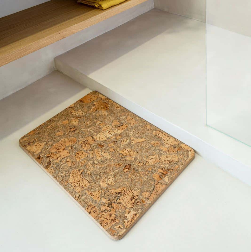 A cork bath mat on the floor beside a walk-in shower