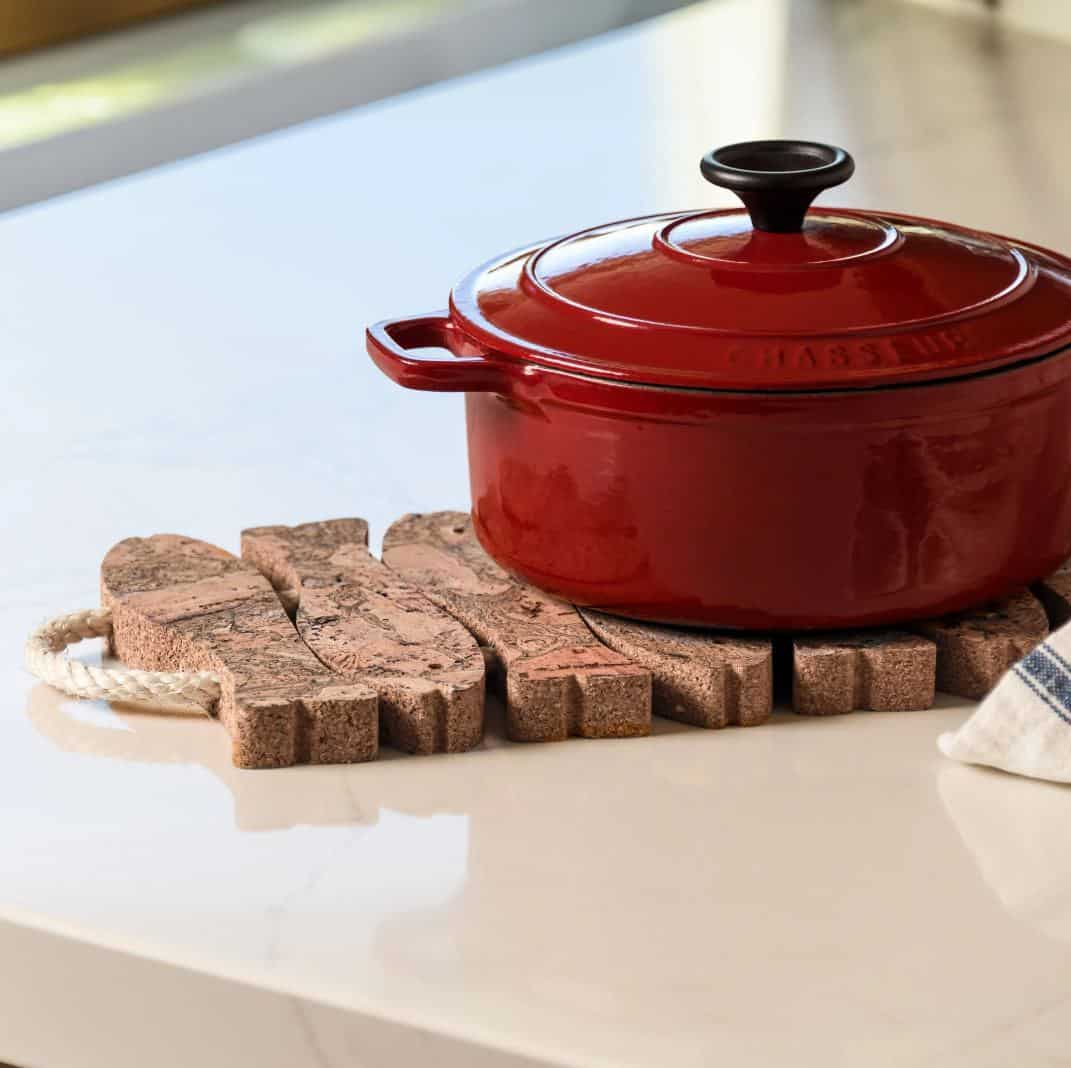 A red pot on a cork trivet shaped like fish