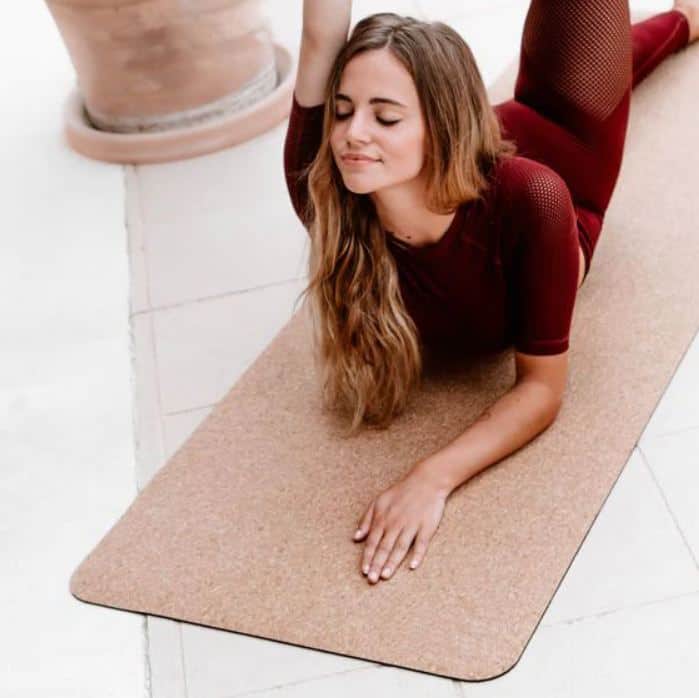 A young woman doing yoga stretches on a cork yoga mat