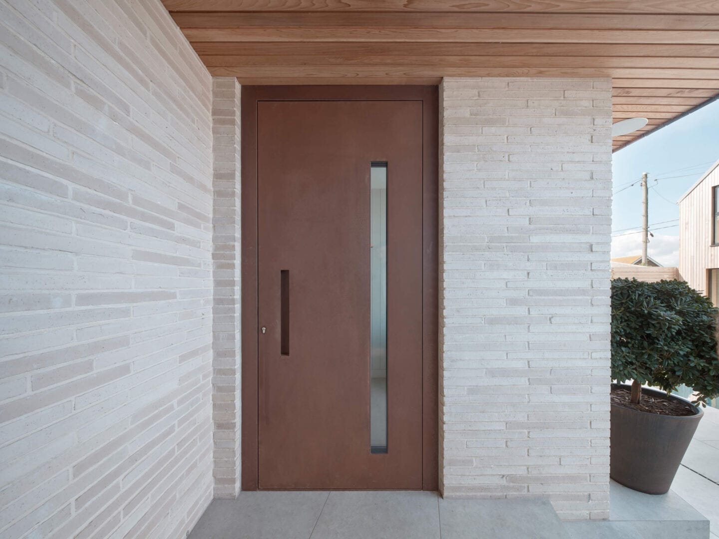 A modern brown steel front door with concealed handle