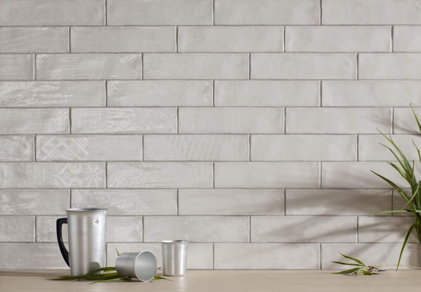 Grey textured tiles with a plant and coffee jug in front