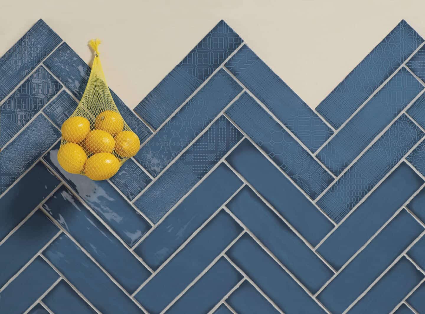 Blue textured wall tiles. A bag of lemons hangs on the wall