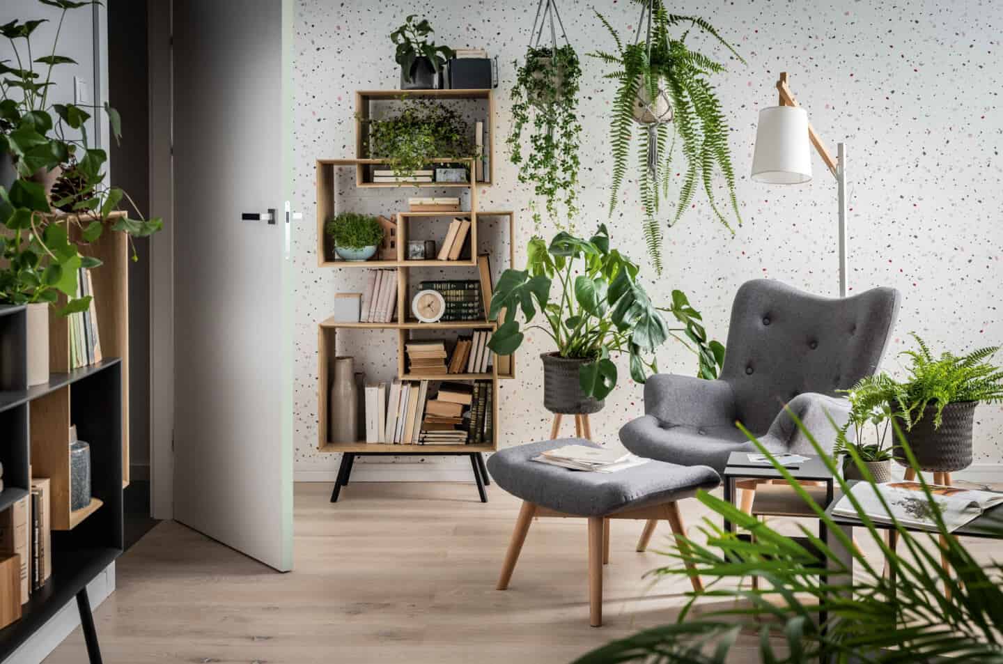 Biophilia in design. Living room and  featuring a grey chair and footstool surrounded by plants.