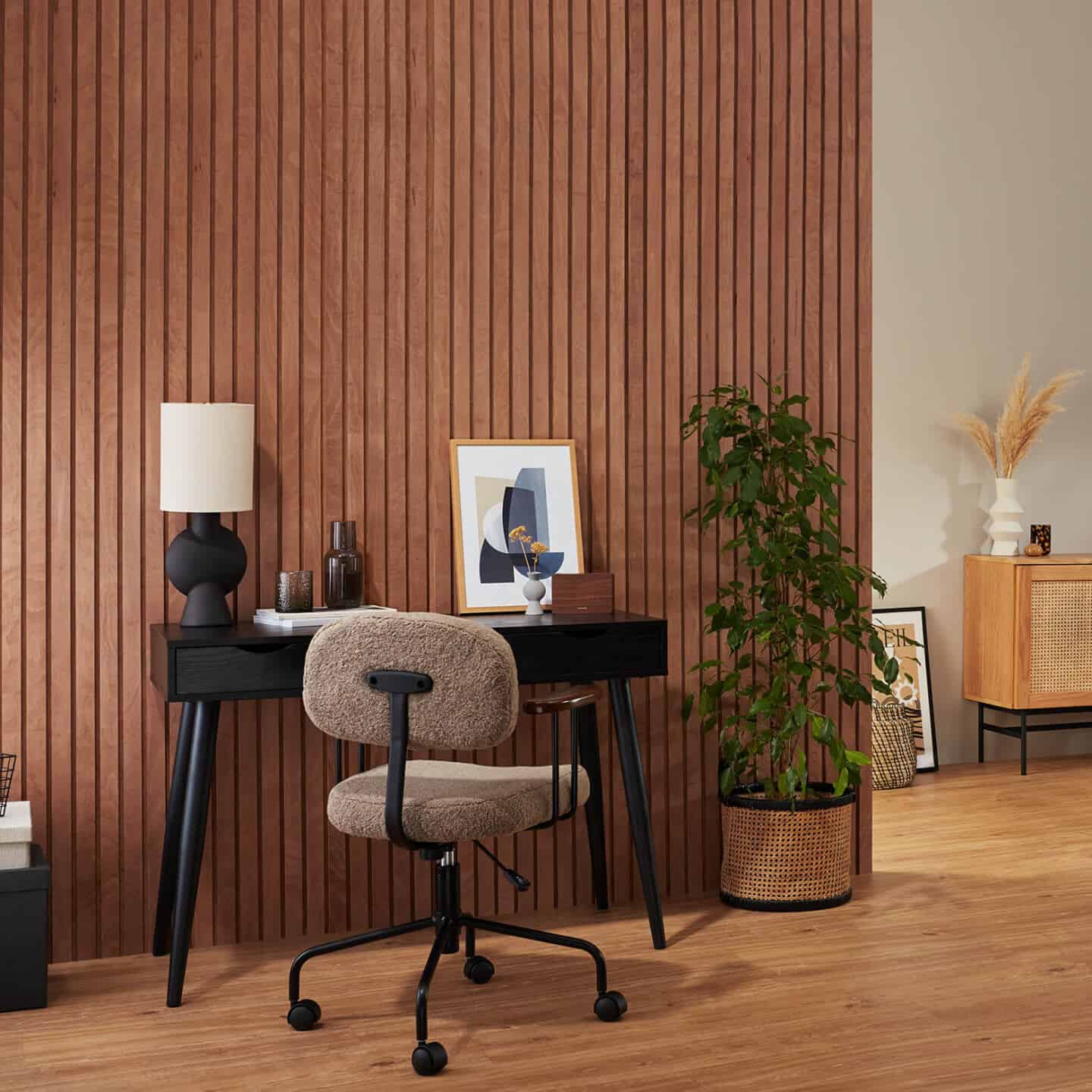 A boyucle office chair from Cult Furniture at a black wooden desk with a fluted wooden wall behind