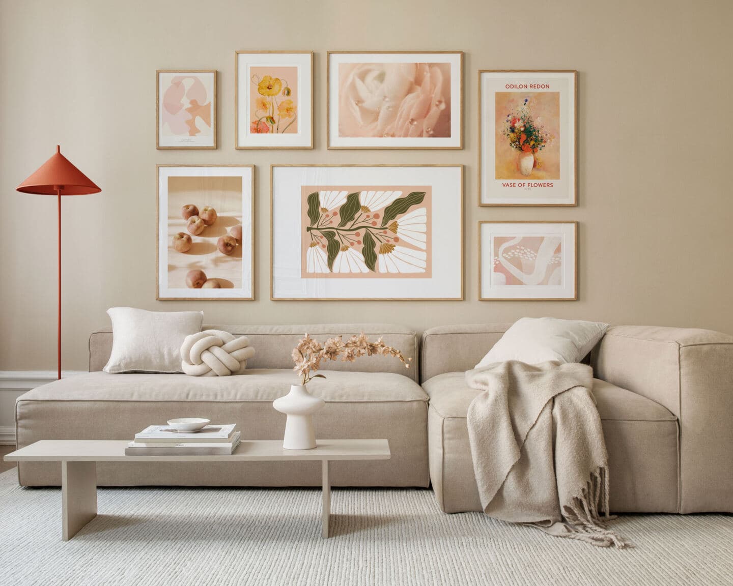 A sofa with a gallery wall on the wall behind featuring peach art work from Desenio