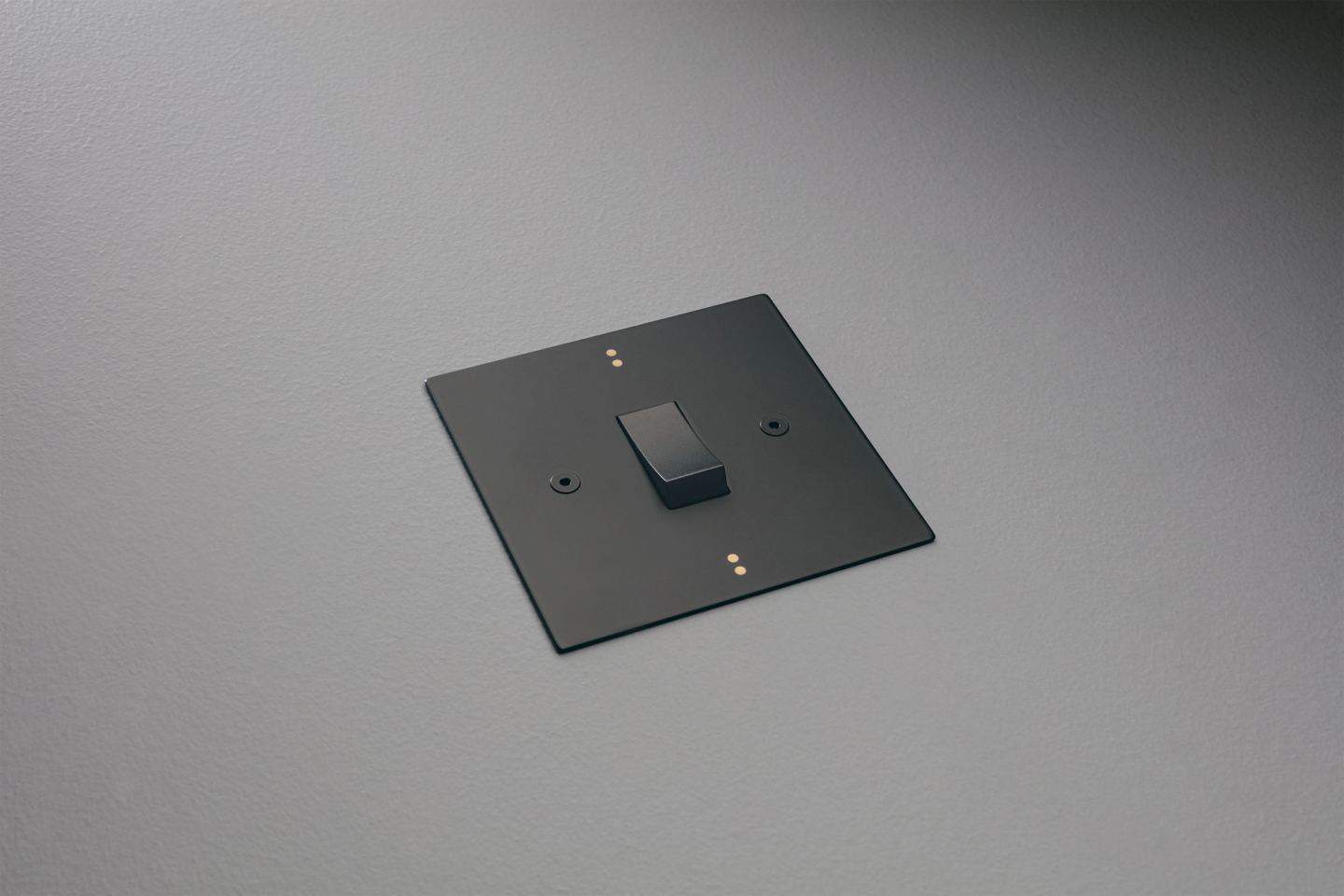 Designer light switches by Kelly Hoppen for Focus SB. Dot is a black light switch featuring two small metallic dots at the top and bottom of the plate.