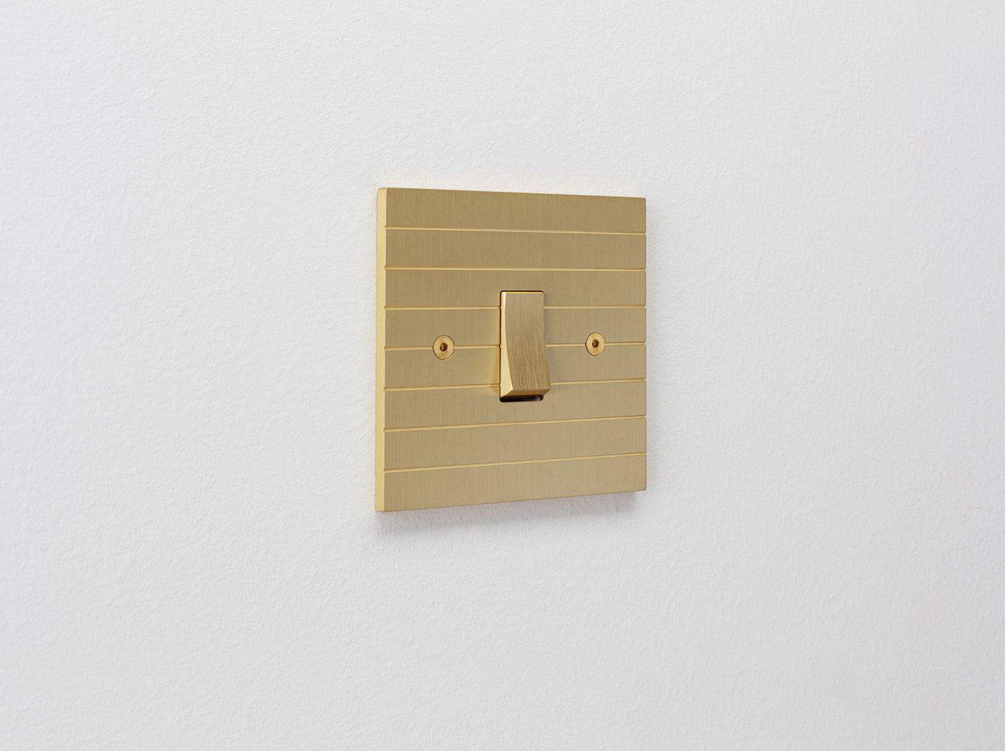 Designer light switches by Kelly Hoppen for Focus SB. Plank is a gold light switch inspired by planks of wood and featuring horizontal grooves.