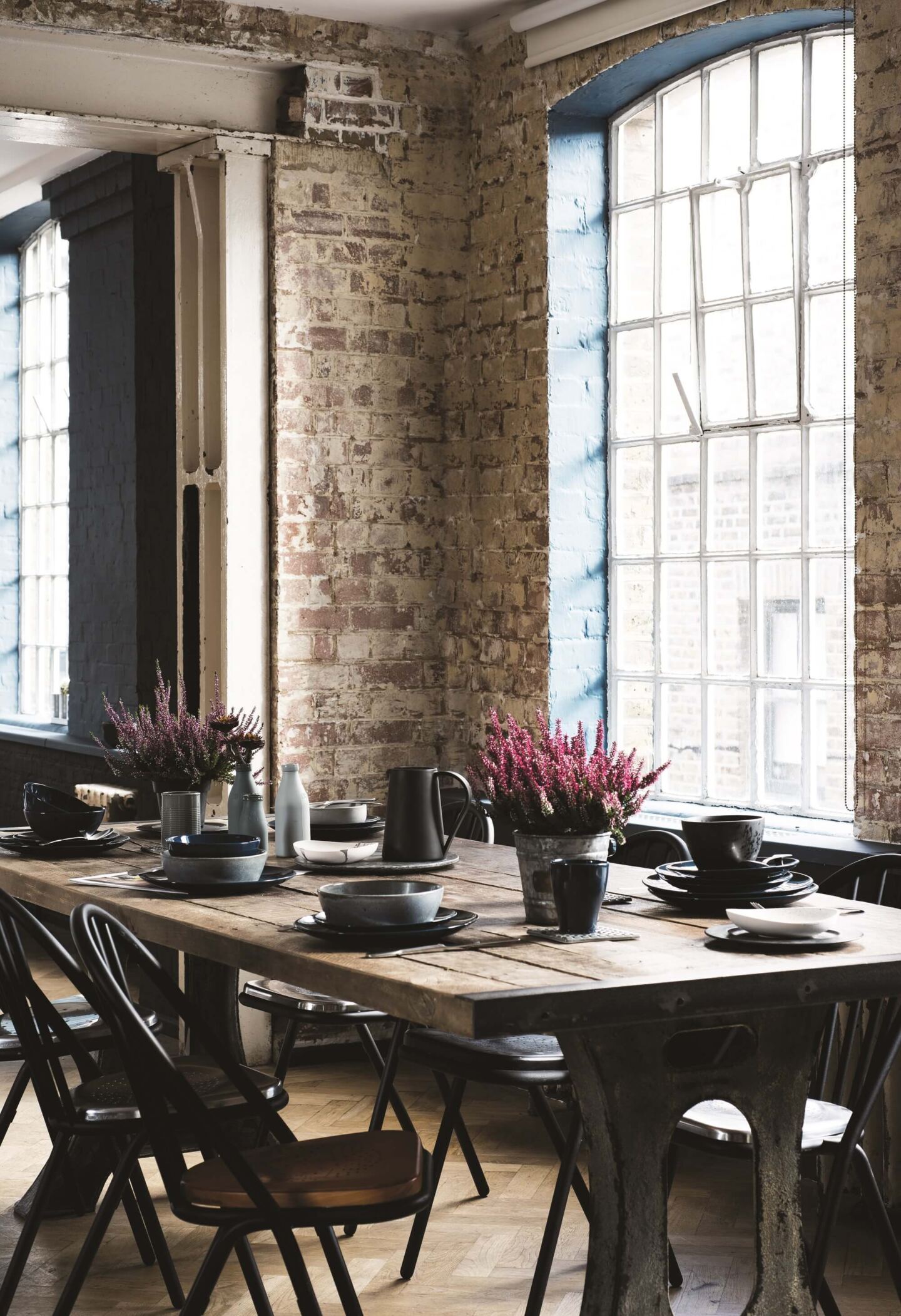 Industrial loft-style dining room.  A large rectangular dining table with 6 chairs around situated in front of industrial windows